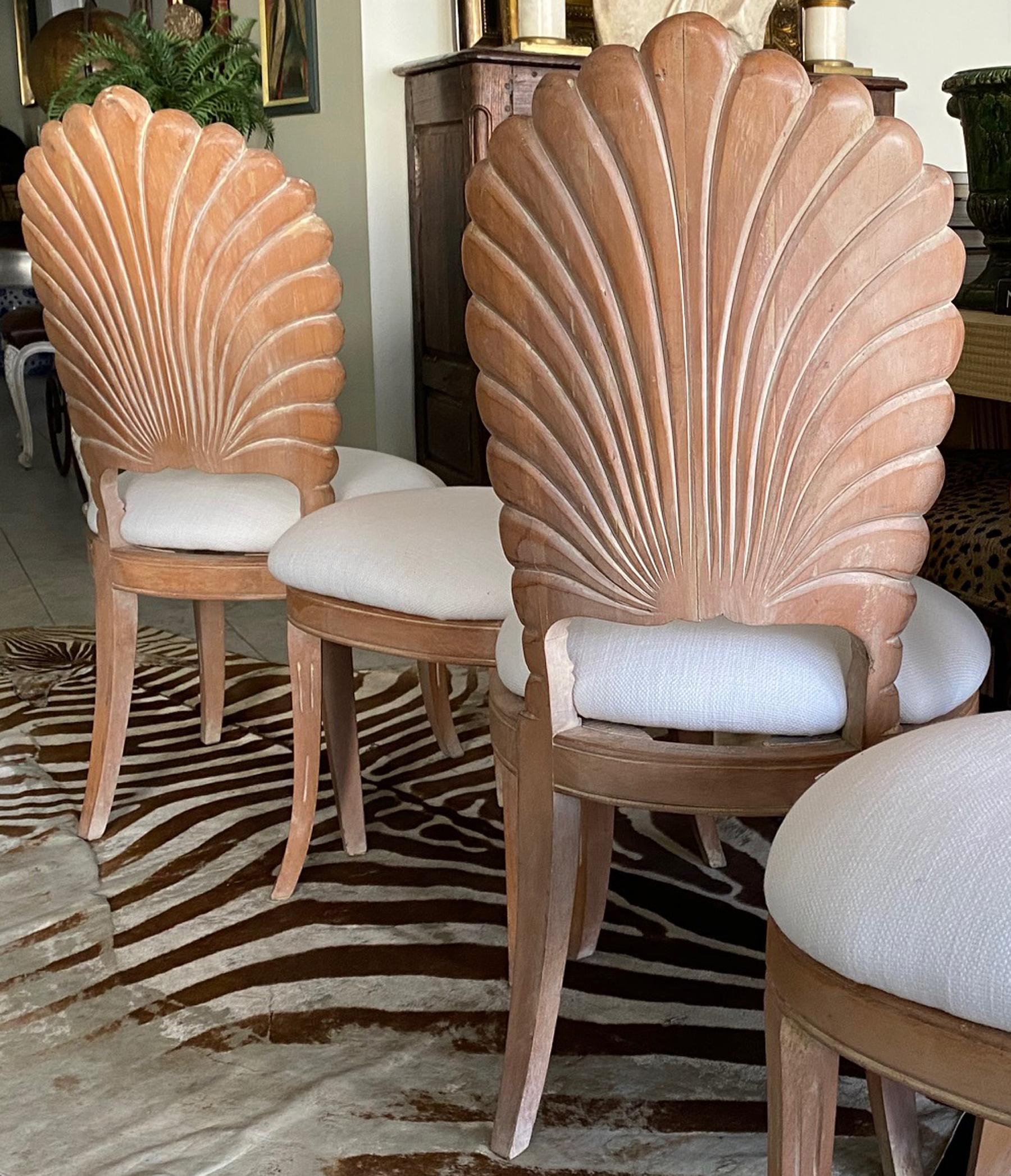 Four shell back dining chairs. These grotto dining chairs were made in Spain. Craved wood shell back chairs with a white wash to clear finish. Newly upholstered seats in white linen fabric make these chairs ready to use.