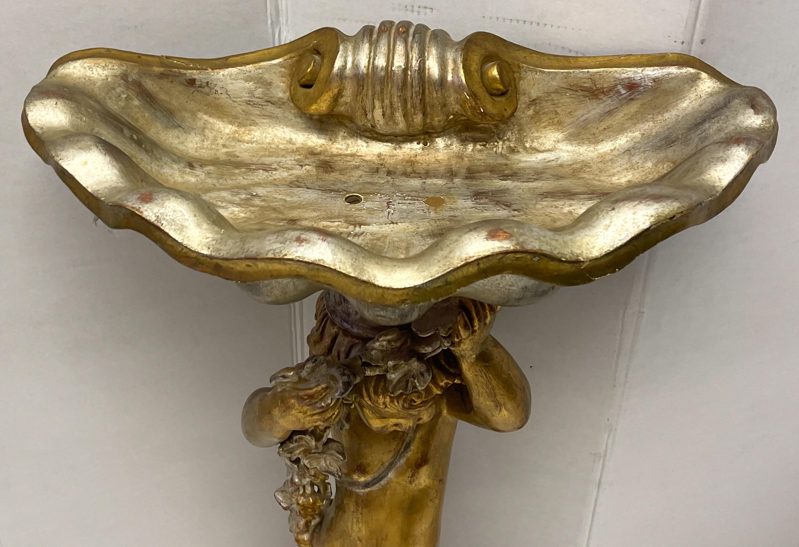This is wonderful! It is an Italian Grotto style carved putti and shell form jardiniere. It is a combination of both silver and gold gilt. The putti is balanced on a shell as well as supporting one.
