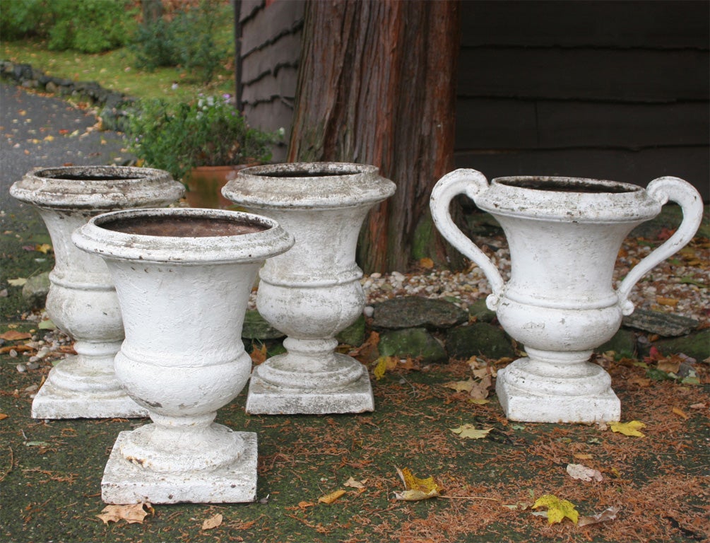 Three identical white painted cast iron urns, single white painted cast iron urn with arms.