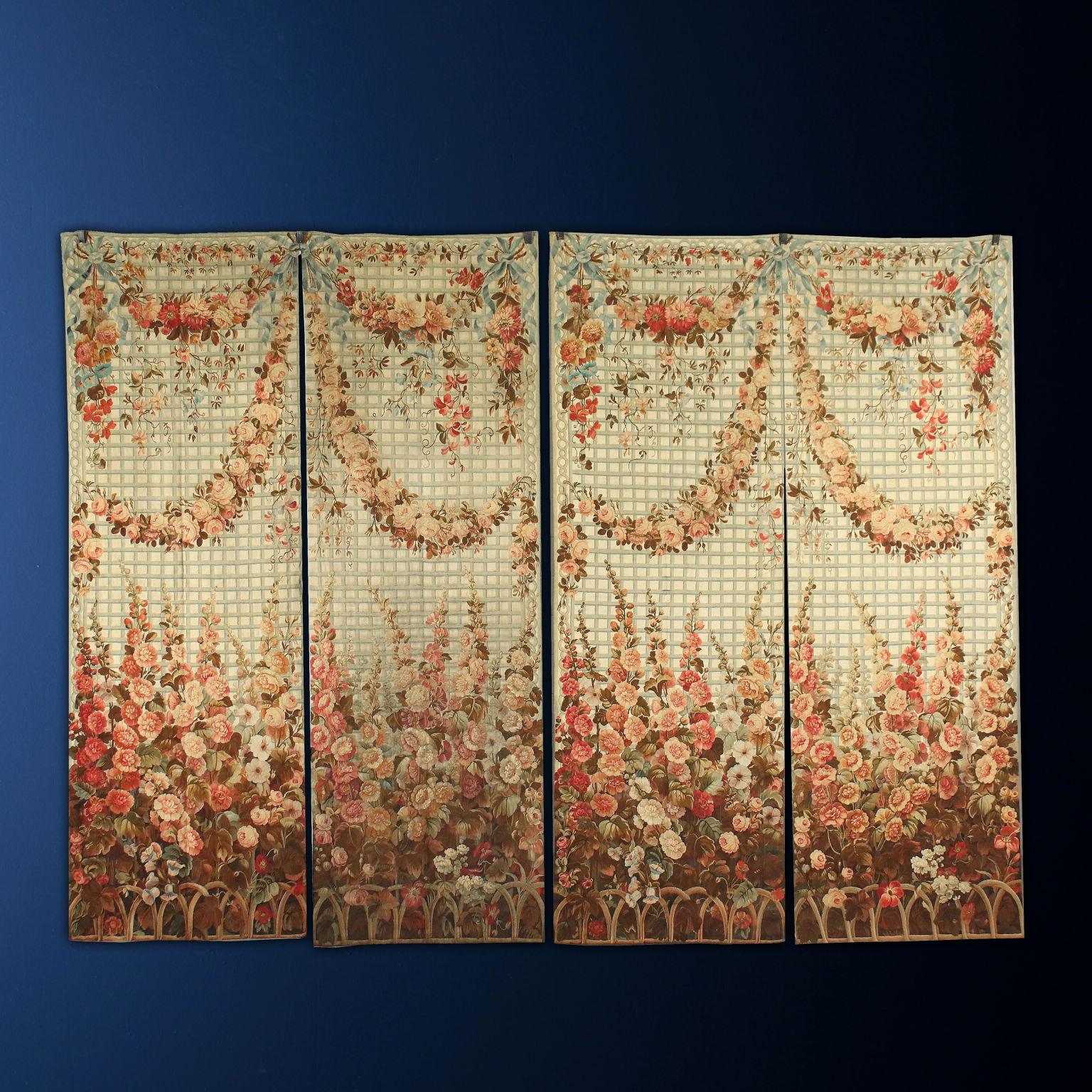 Group of four wool tapestries in which, on a light background, a pergola with floral borders and festoons is represented, characterized by a great variety of species always in light colors tending to pink and peach, held back by cerulean bows and
