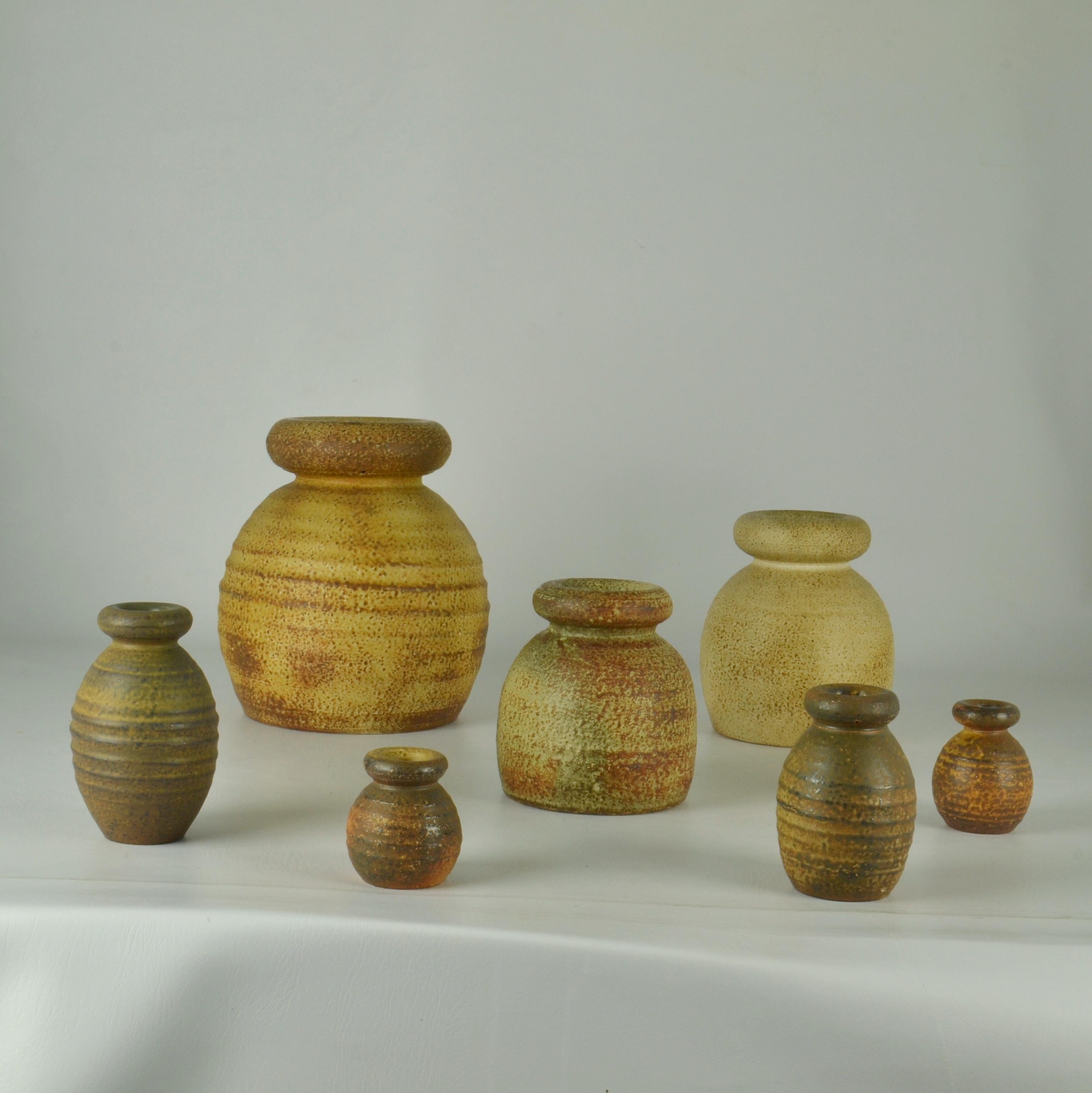 Set of seven Studio Pottery turned bulbous vases with rolled tire-shape necks Mid-Century Modern, glazed in ocher and natural earth tones and in various heights by Mobach's Dutch ceramist Piet Knepper are made in the 1970s. The glazes made of