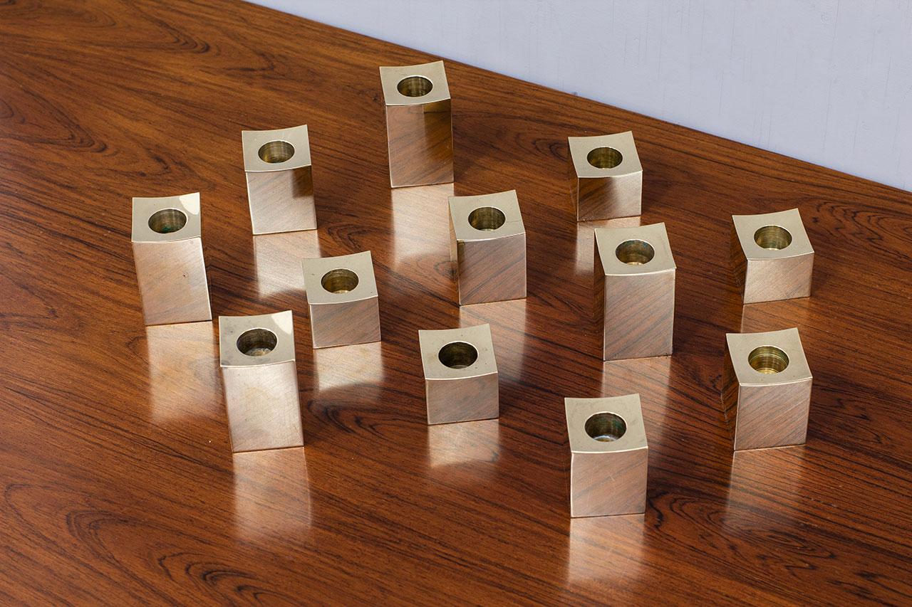 Elegant group of twelve solid brass candlesticks. Manufactured by Gusum
Metallslöjden in Sweden during the 1980s. Each candlestick is stamped and engraved with a date. Made from solid polished brass in a cubic shape (parallelepiped base). All