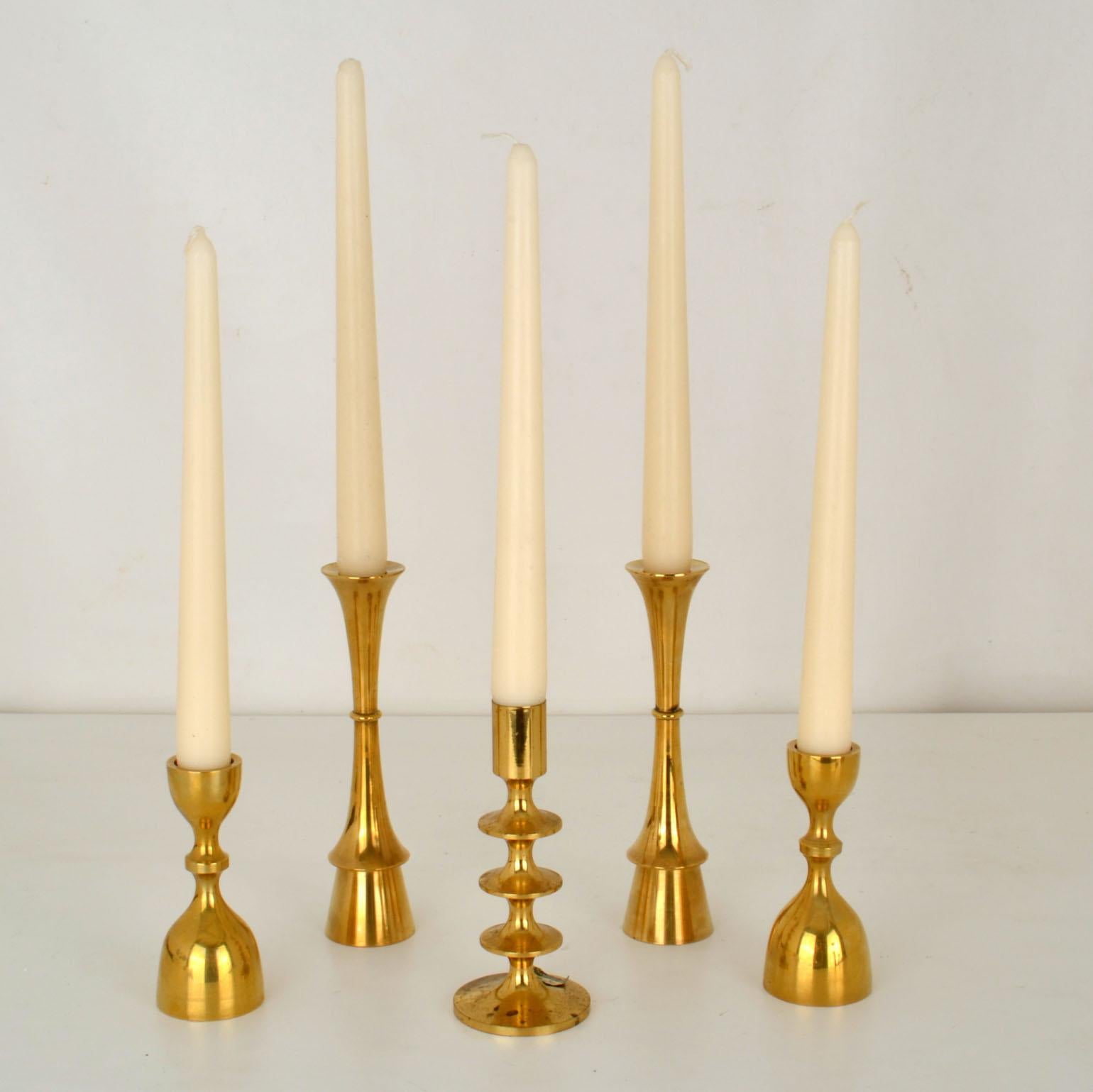Five solid brass Mid-Century Modern candle holders, 2 pairs and a single for regular candles. The tall one is by Hyslop. The middle one is labelled SKS Design
Measures: Heights: 18-16-11 cm 
Diameter: 4-6-4.5 cm.

 