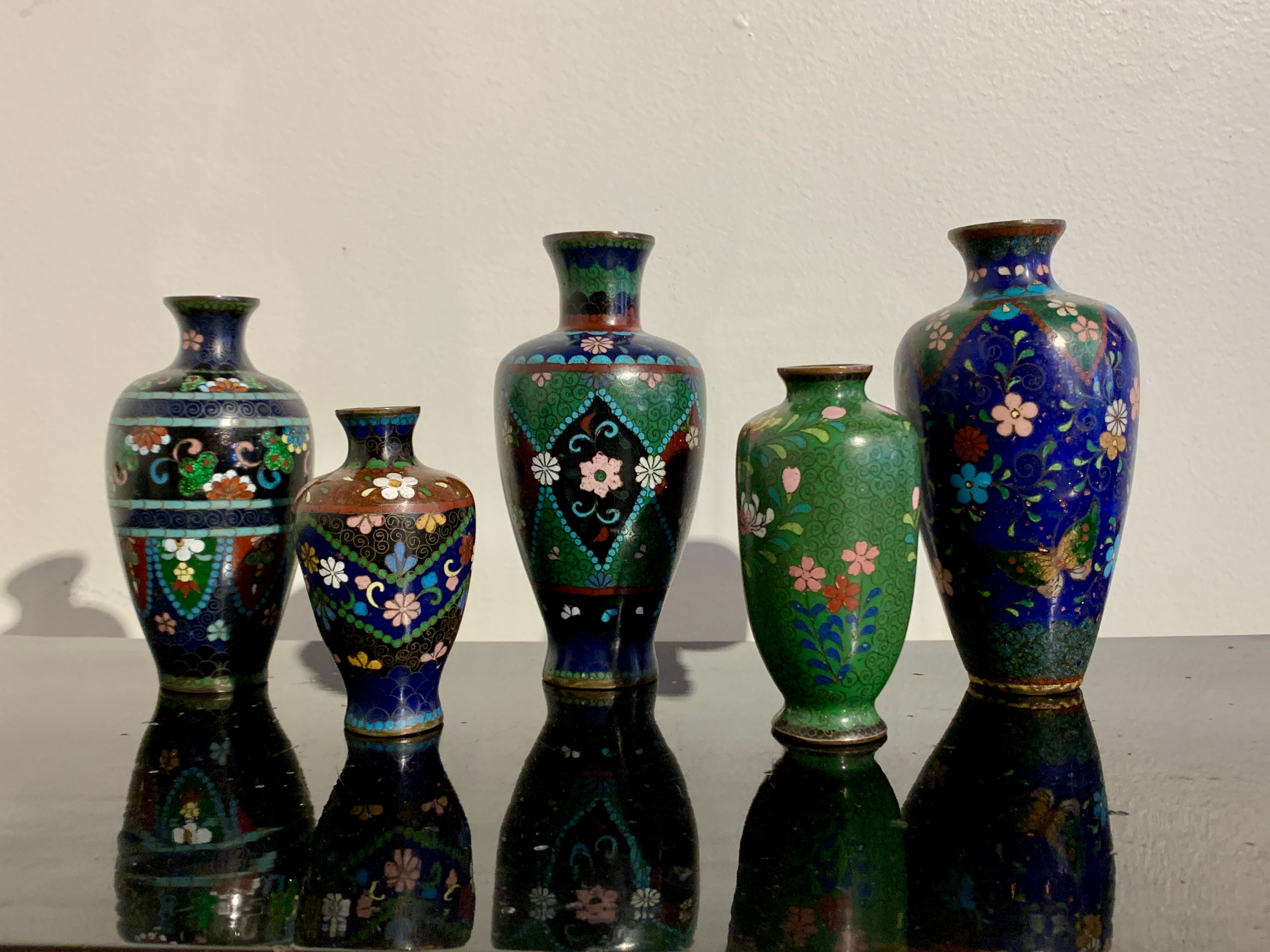 A delightful group of five small Japanese cloisonné vases in various colors and designs, Meiji period, early 20th century, Japan.

The vases all of baluster form and decorated in the cloisonné technique with goldstone highlights. 

Vase 1: Dark blue