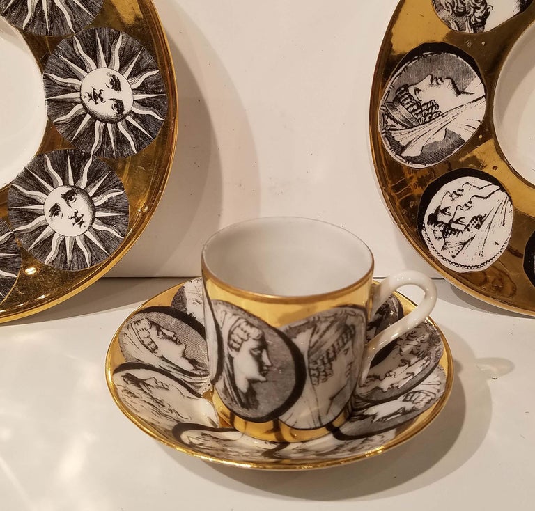 Group of Fornasetti Milano espresso cup & saucer plus 2 Fornasetti under plates. cup and saucer set made in Italy by Fornasetti - Milano in the Monete pattern. The set is in good condition with light wear to the gold. No chips, cracks, crazing,