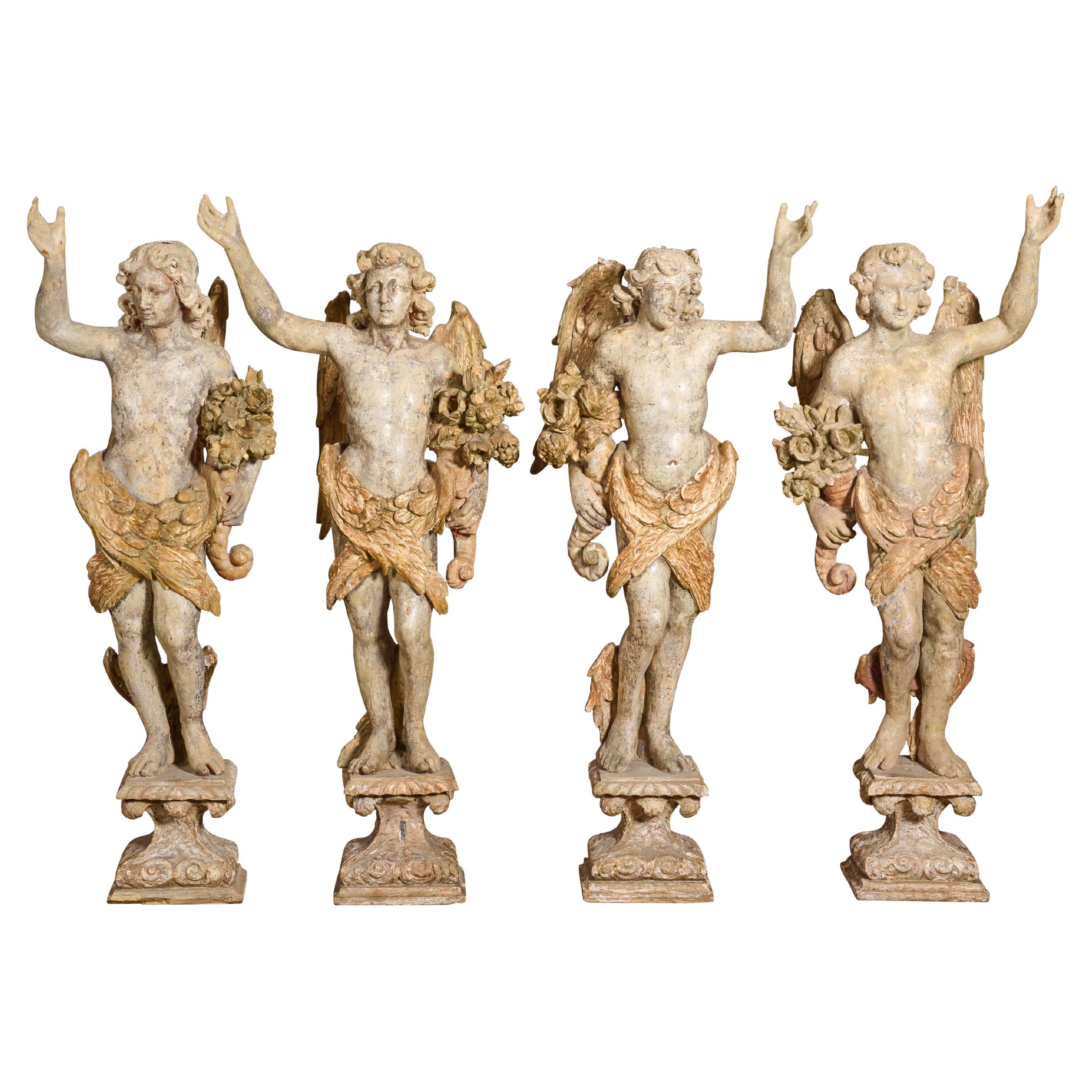 Groupe de quatre anges ailés en bois sculpté et gesso
