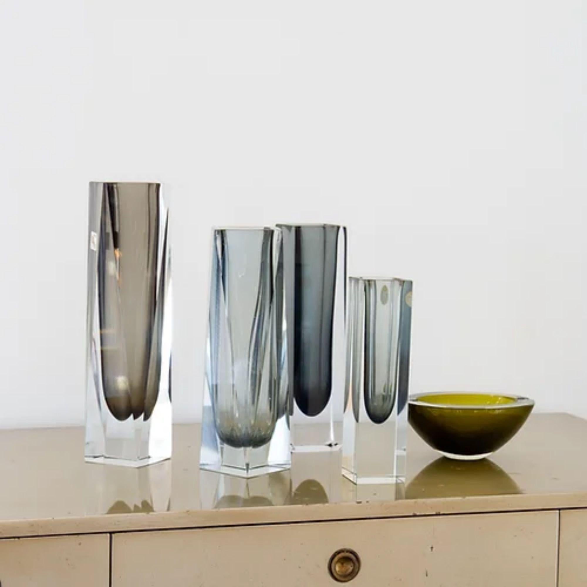 A group of charcoal Murano glass vases and an ashtray comprising of:

A Large Unusual Facet Cut Murano Sommerso Glass Vase with a Charcoal Centre Cased in Clear Glass stamped, small chip to bottom corner.
30.5cms high x 7.5cms square

A Rectangular