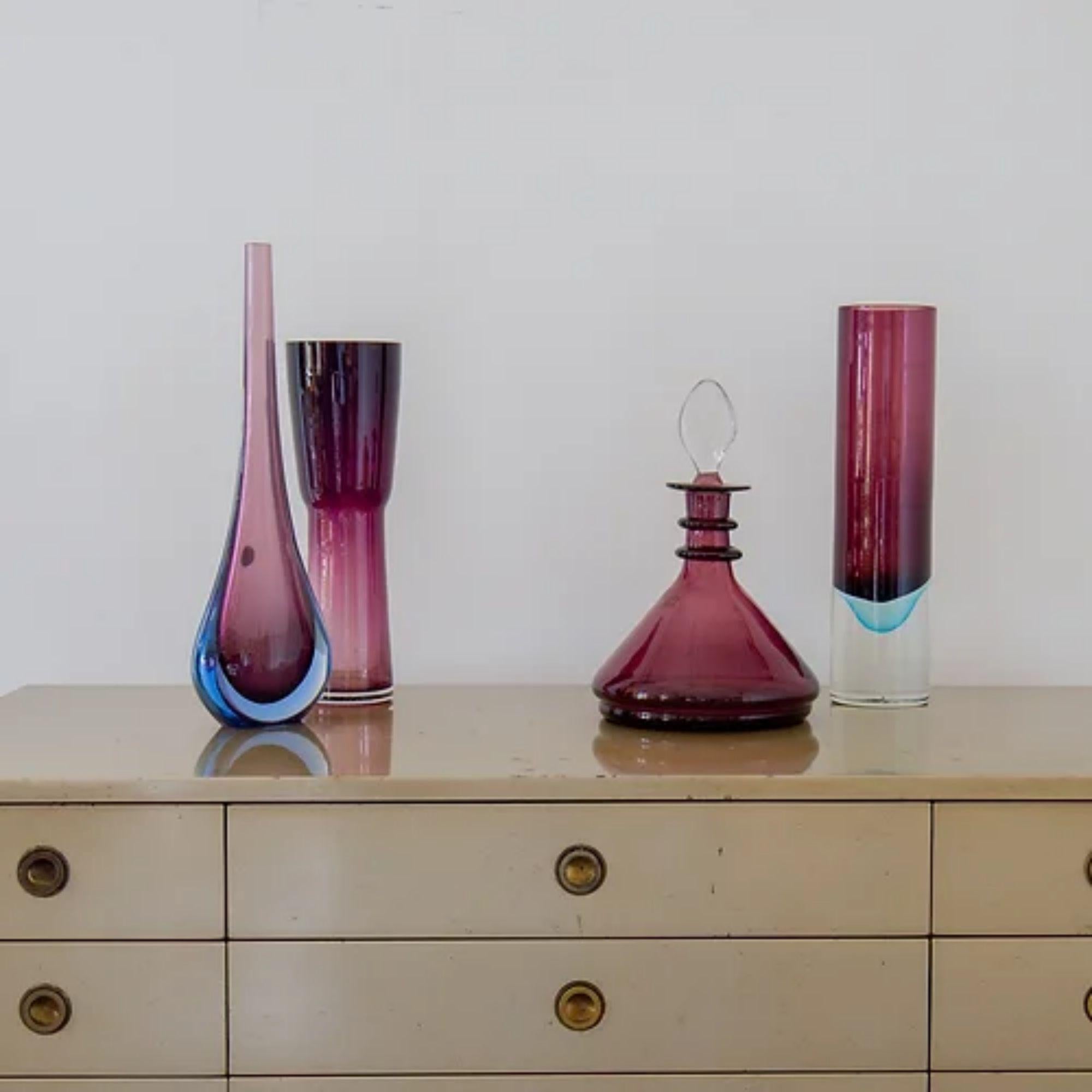 A group of four plum purple glass vases comprising of:

A Tall Cyclindrical Sommerso Glass Vase with a Rich Plum and Turquoise Centre Cased Clear Air Bubbled Glass
32cms high x 8cms diameter

A Plum Glass Decanter by The Blenko Glass Company of