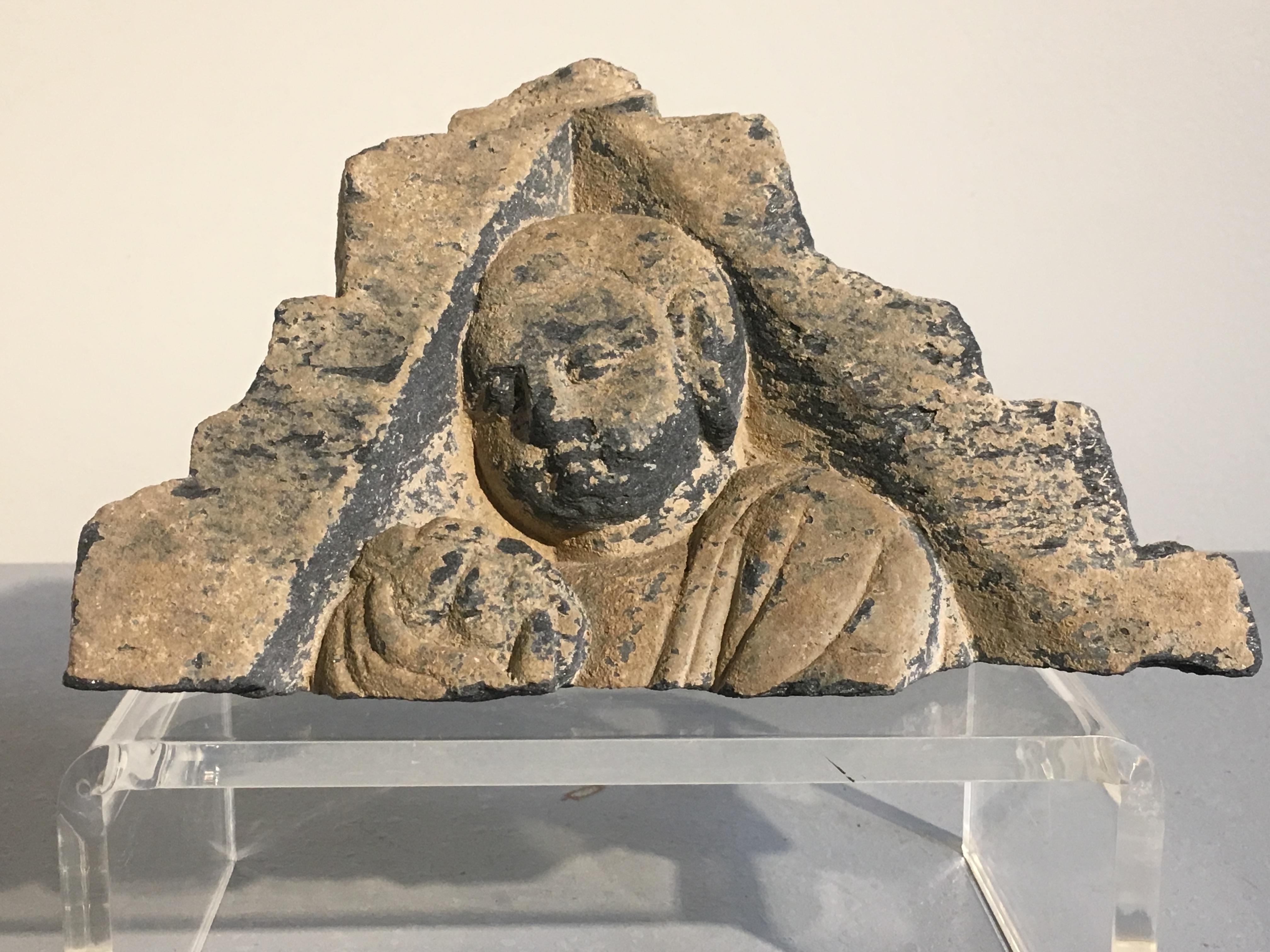 An interesting group of sculptural fragments from the ancient Kingdom of Gandhara, circa 3rd-5th century.
The group consists of a triangular shaped fragment with an image of a monk holding up an offering. This image may represent the final scene in