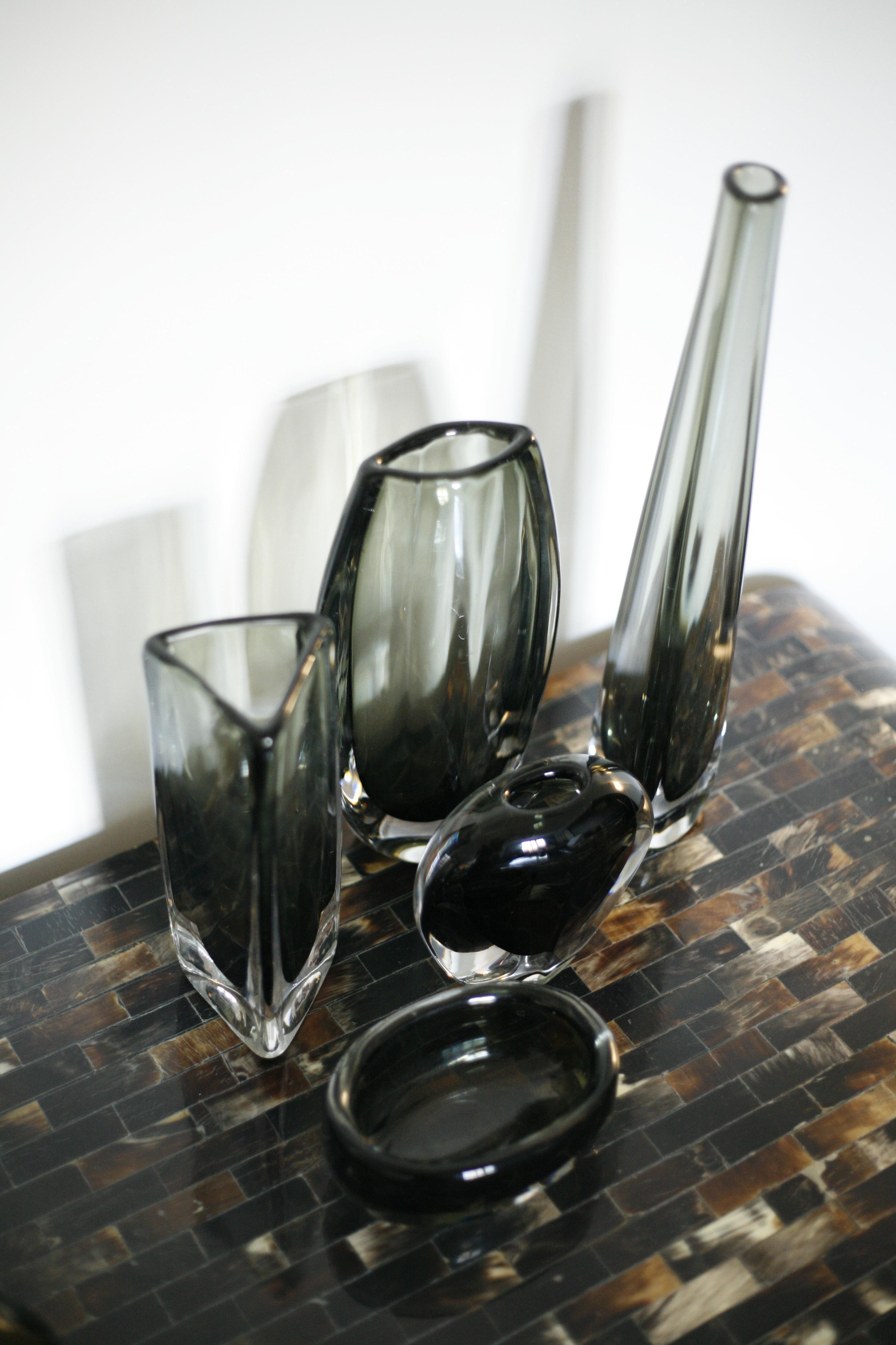 Group of green Orrefors crystal glass vases in various shapes surrounded by a thick layer of clear glass.
These are all by Nils Landberg 1950s signed Orrefors.