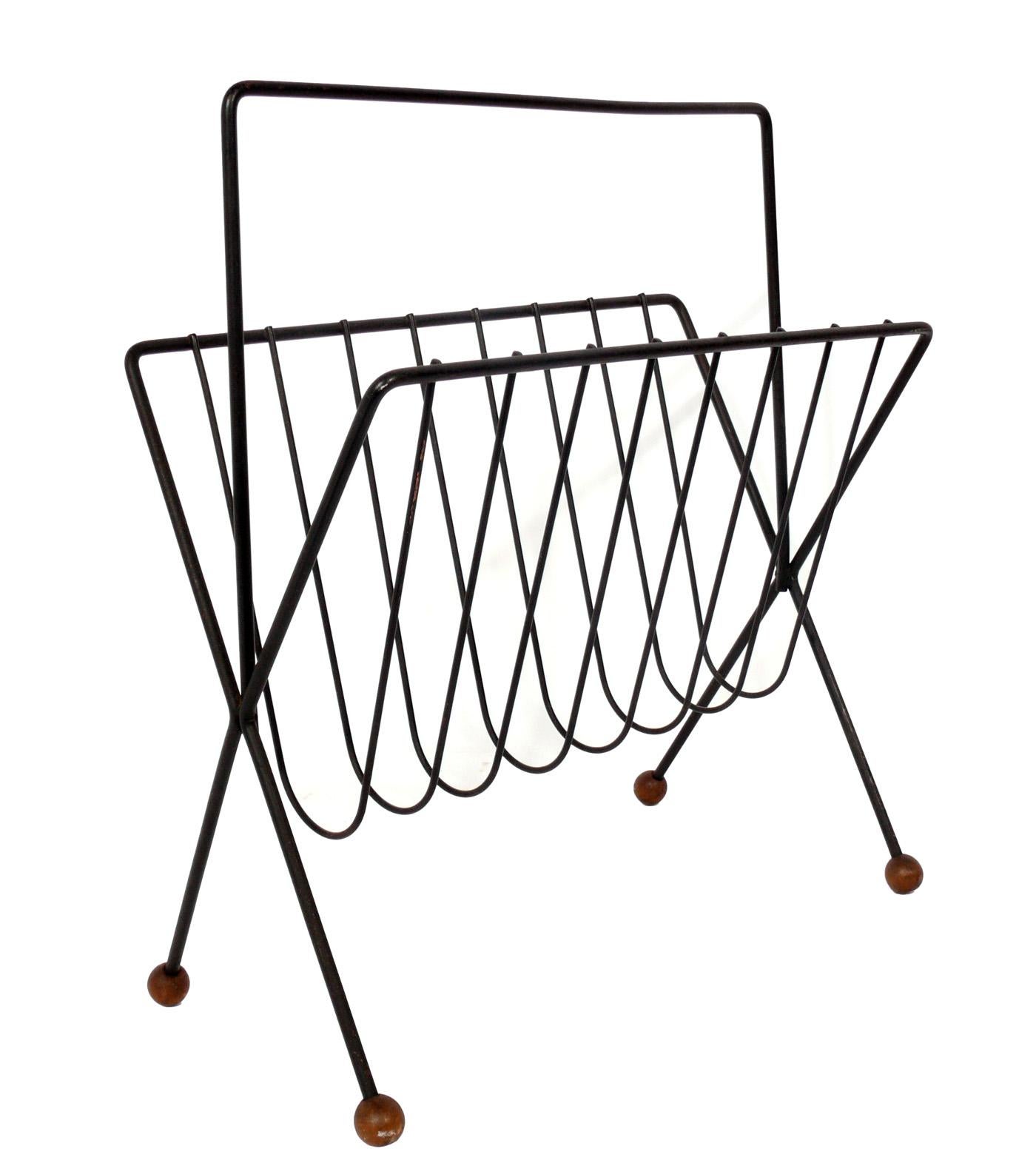 Selection of Mid-Century Modern magazine racks, circa 1950s. They are:
1) Sculptural iron magazine rack, designed by Tony Paul, seen at the left. It measures 20.25
