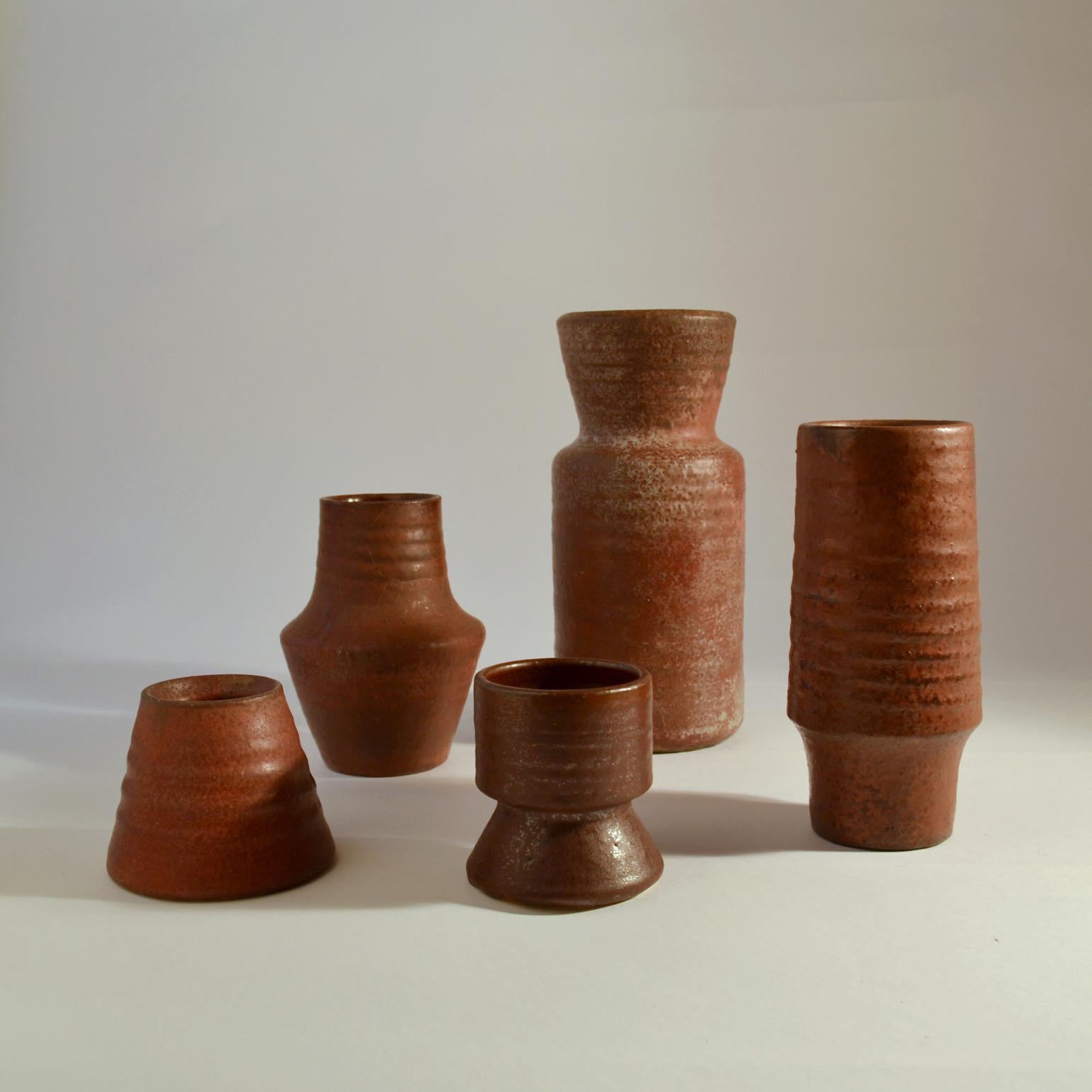 Five studio pottery vases of various heights in red tones and in compatible forms. They are like sculptures with a natural rough character created on the turning wheel by highly technical skilled Dutch ceramist in the 1960s . The glazes made of