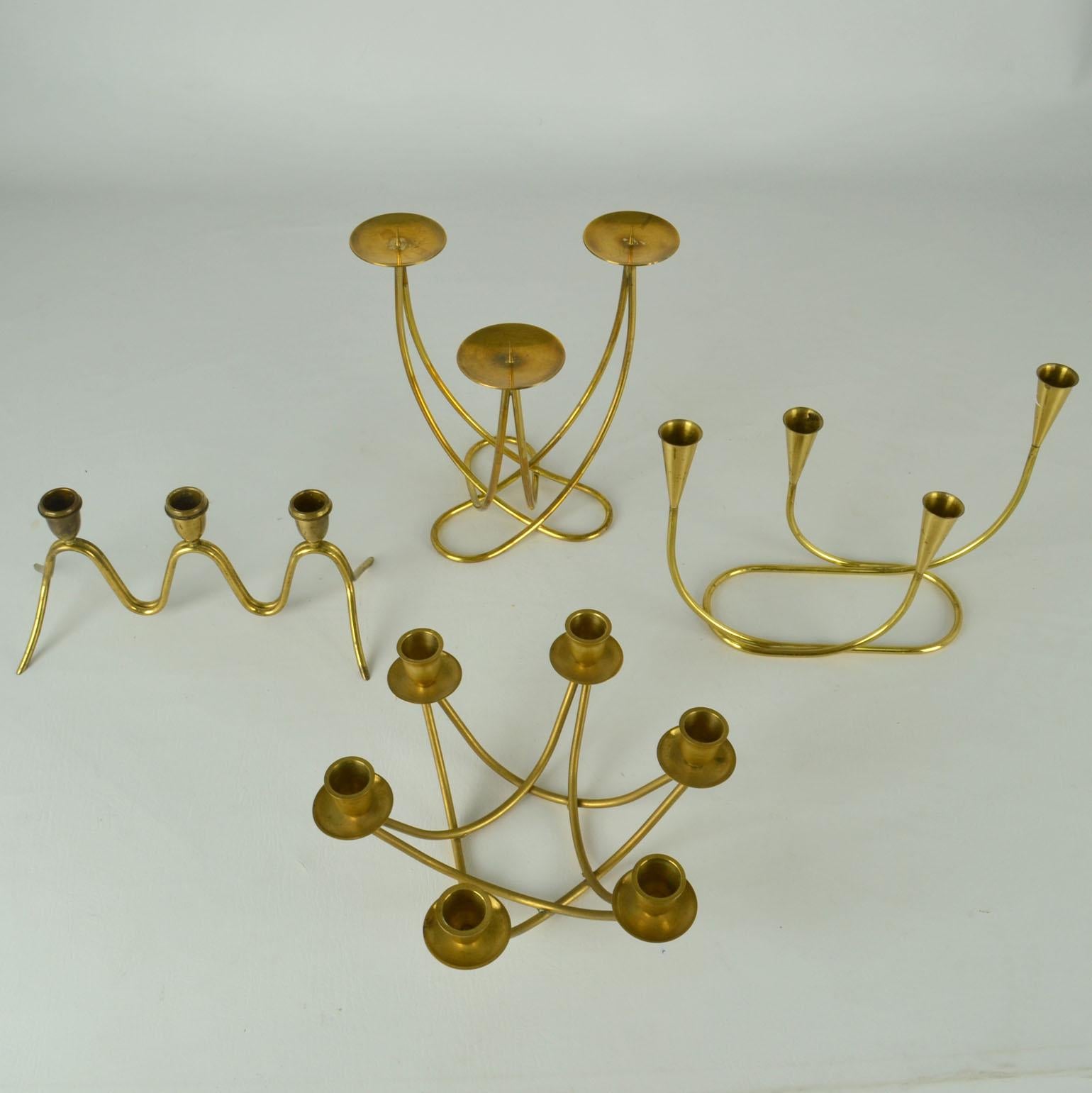 Group of four brass candelabras with organic curves.
One for six regular candles, two for three regular candles and one for three wider candles (D 3-4 cm).