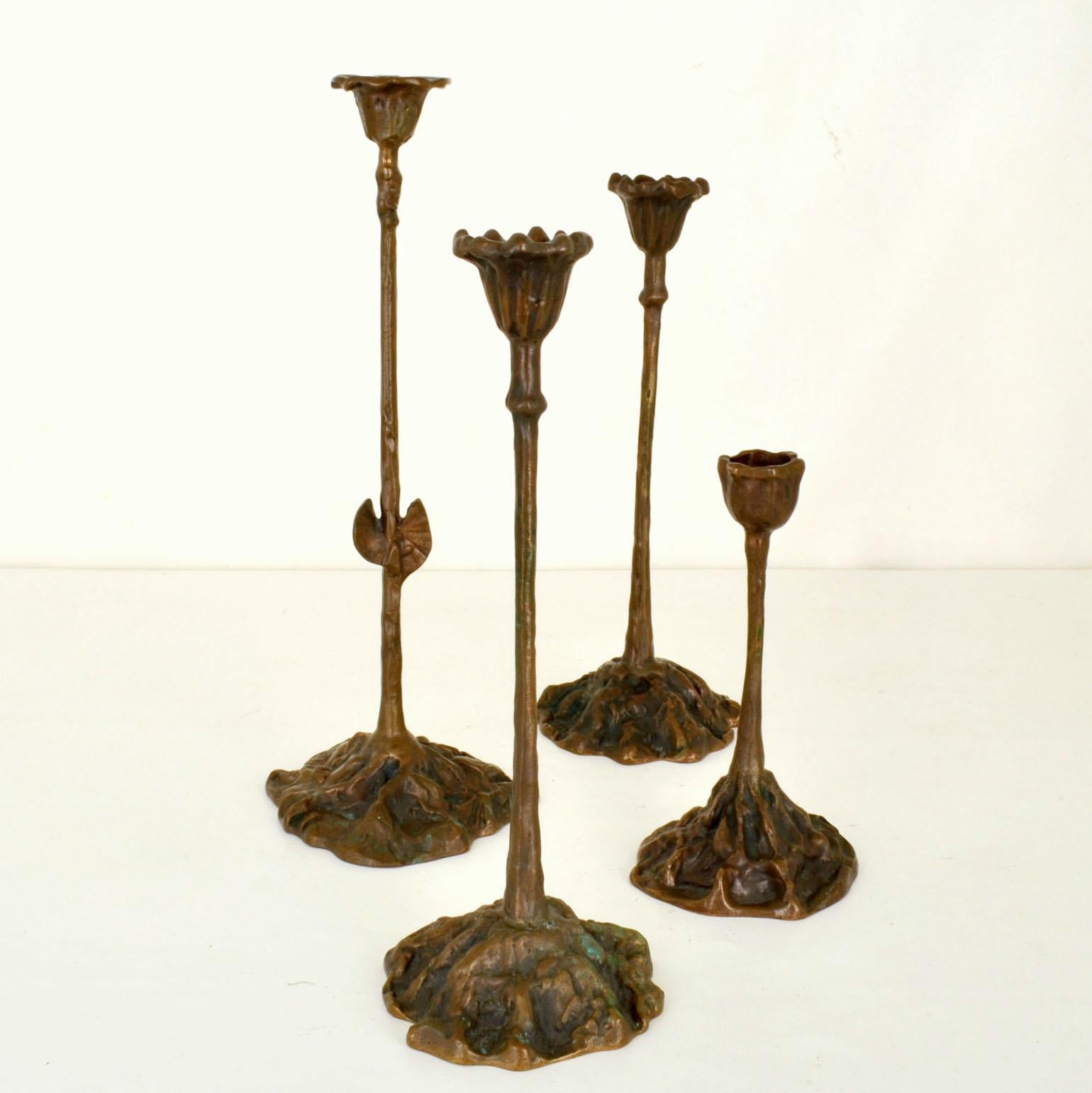 Group of four candle holders on different heights cast bronze in organic design expressing growth of plants from rooted bases. They are designed for regular candles. The bronze finish has its original patina that is close to nature with fragments of