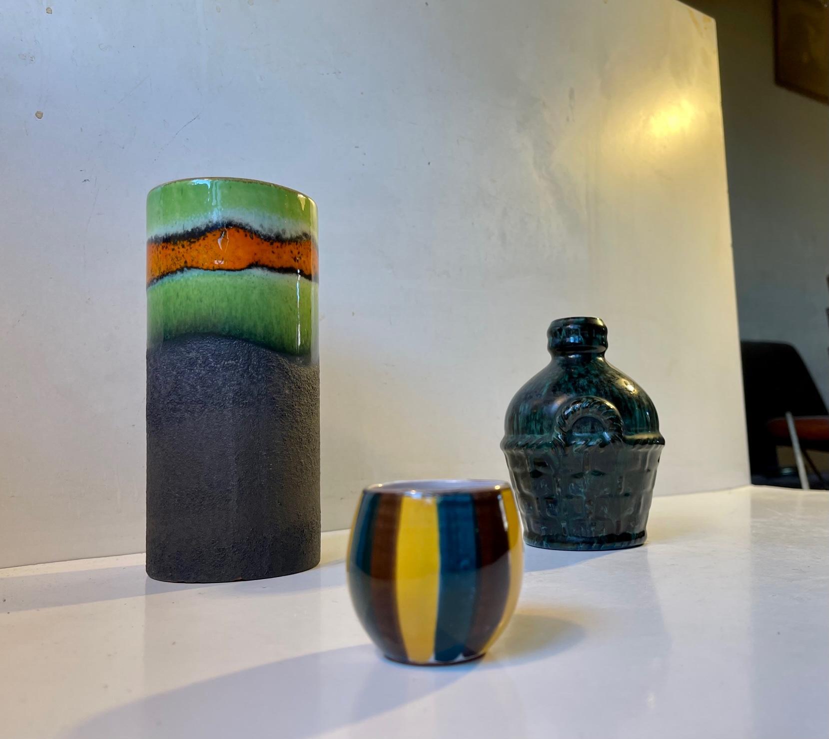 Mixed/curated group of 3 Scandinavian ceramic/stoneware pieces. A cylindrical vase with green and orange glaze, a wine-bottle shaped vase in green and black glaze and a small striped vase/cup. All studio made in Denmark/Scandinavia between 1950-80.