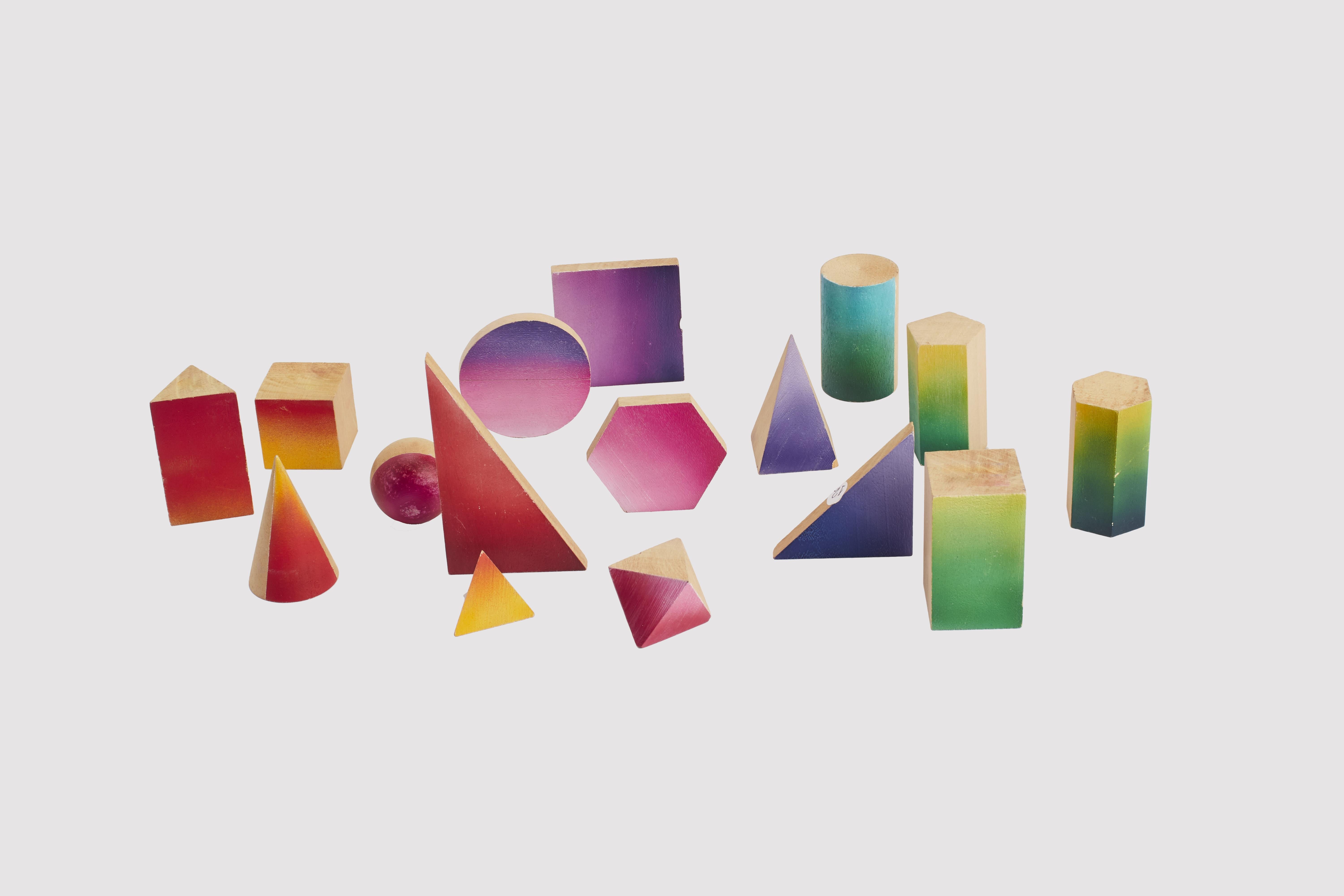 Gruppo di 16 piccoli modelli geometrici in legno massiccio per l'insegnamento in classe. Una faccia di ciascuna è colorata seguendo la scala cromatica dei colori. Paravia, Italia, inizio XX secolo.