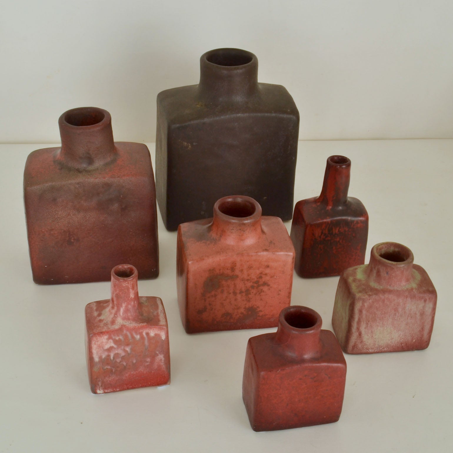 Group of seven Mid-Century Modern square studio pottery vases and long round necks are glazed in dark red tones. They are hand formed and in different heights by Mobach Dutch ceramist in the 1960's. 
The multi color glazes are made of natural