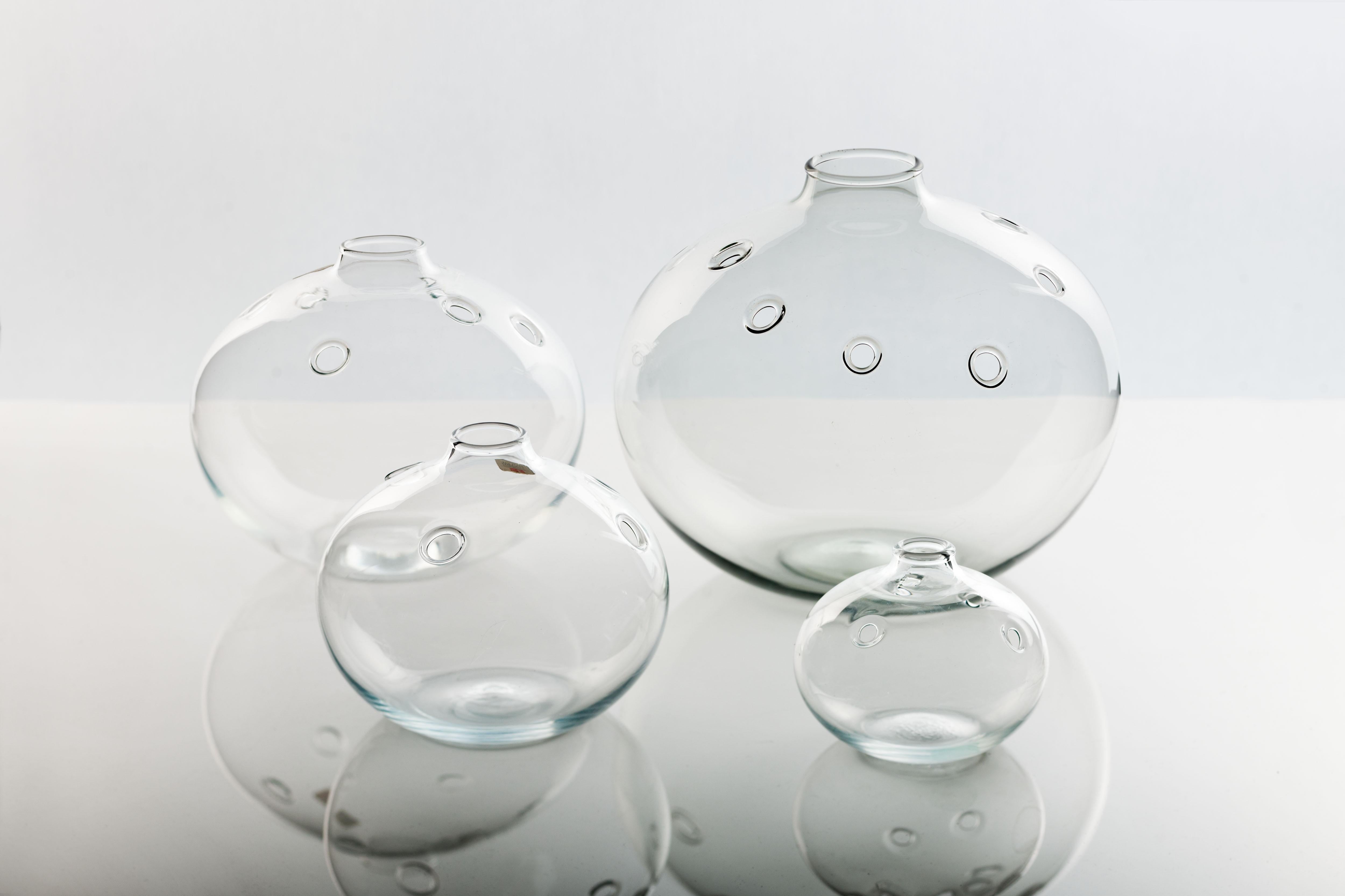 Set of four sizes mouth blown clear glass Hull (hole) vases, designed by Michael Bang for Holmegaard Denmark, 1970s. Produced between 1973-1978.
Vases are executed with holes to place and arrange flowers in. 
Each individual vase is signed with