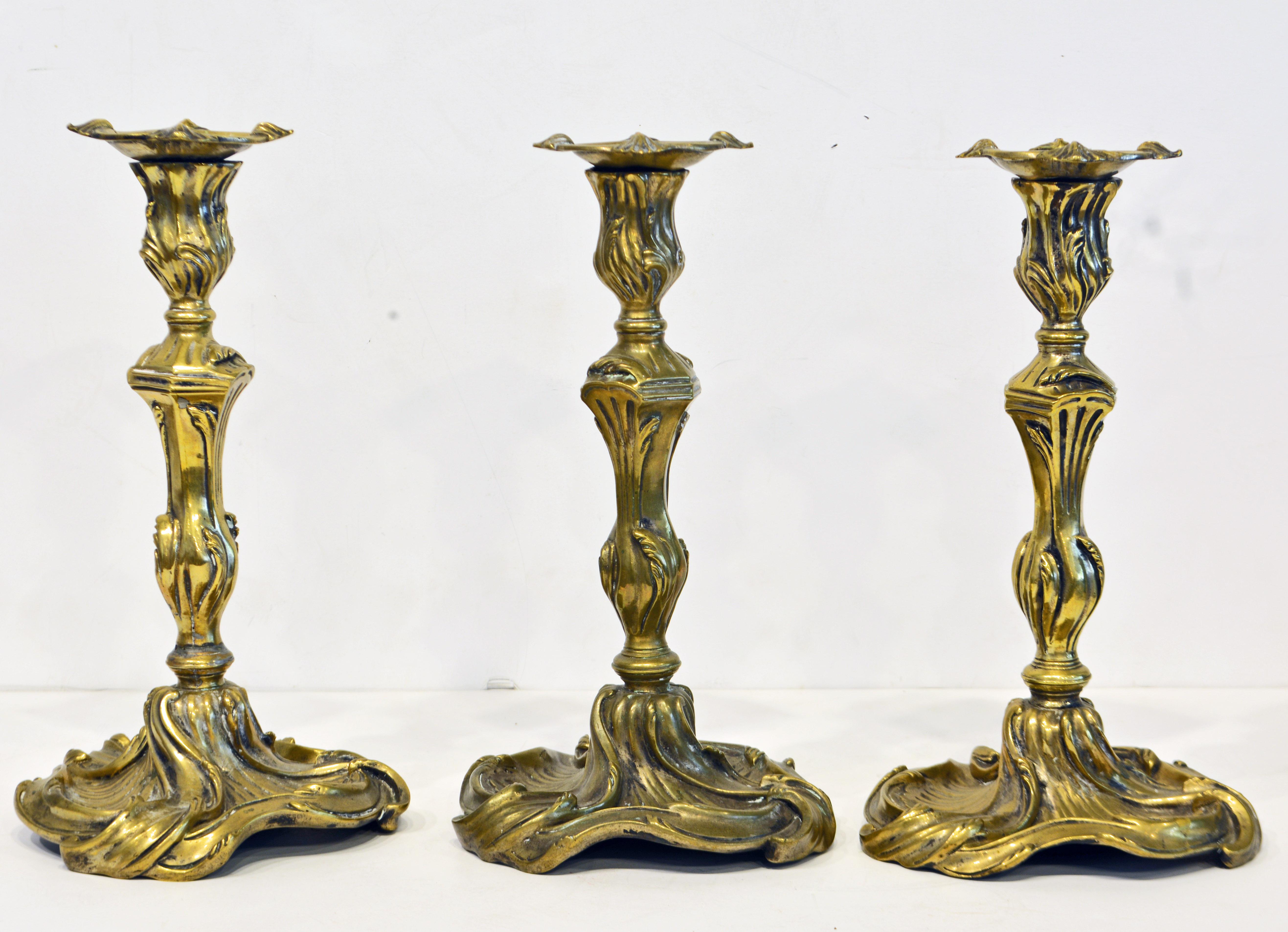 Boldly modeled in the French Louis XV style with sweeping scrolls in an organic composition this group of three bronze candlesticks are quite rare, since these sticks usually come in pairs. The date to the mid-19th century.