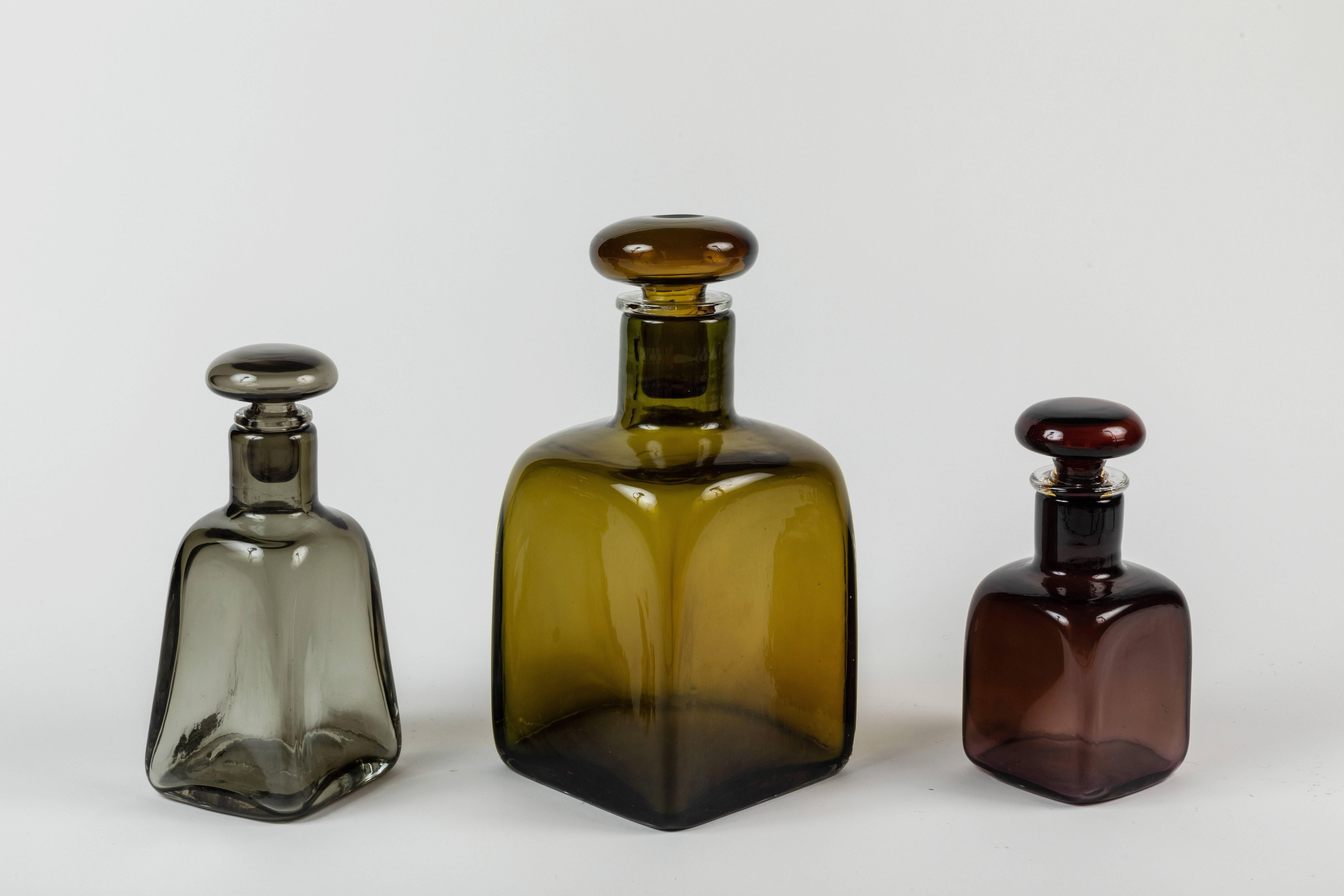A group of three glass bottles with stoppers by one of the leading figures in the production of Murano glass, and an important contributor to 20th-century design, Paolo Venini (1895 - 1959). Bottles are each a different color cased glass while the