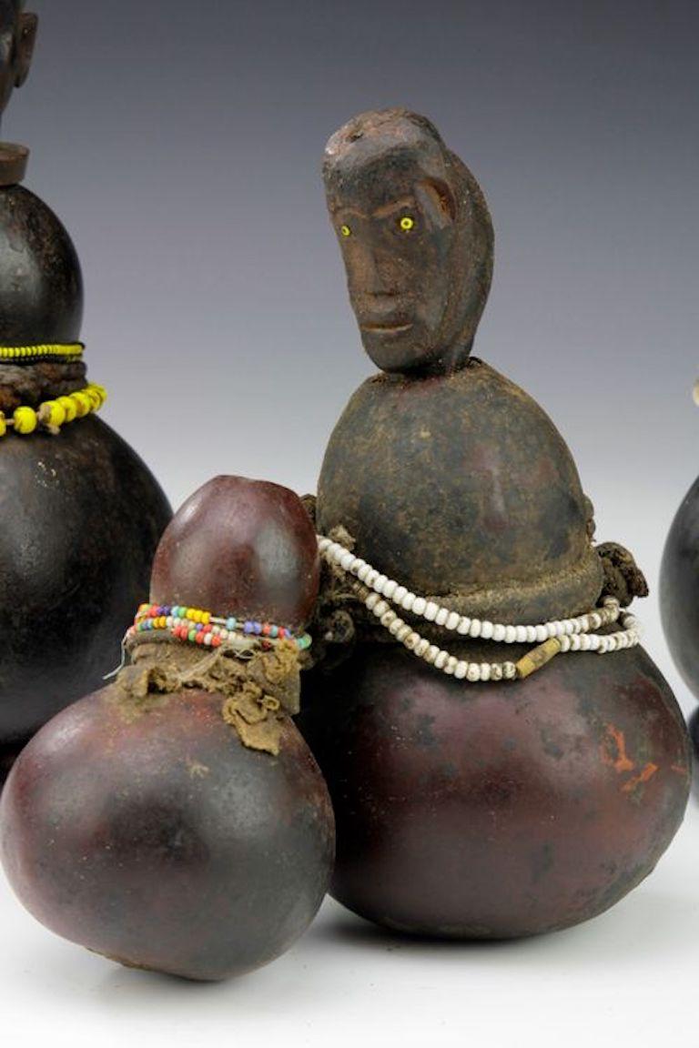 Vendidos como colección, cada uno de estos recipientes medicinales presenta sus propias características distintivas. Uno de los recipientes de calabaza presenta un tapón de madera tallada que representa una cabeza masculina con grandes orejas