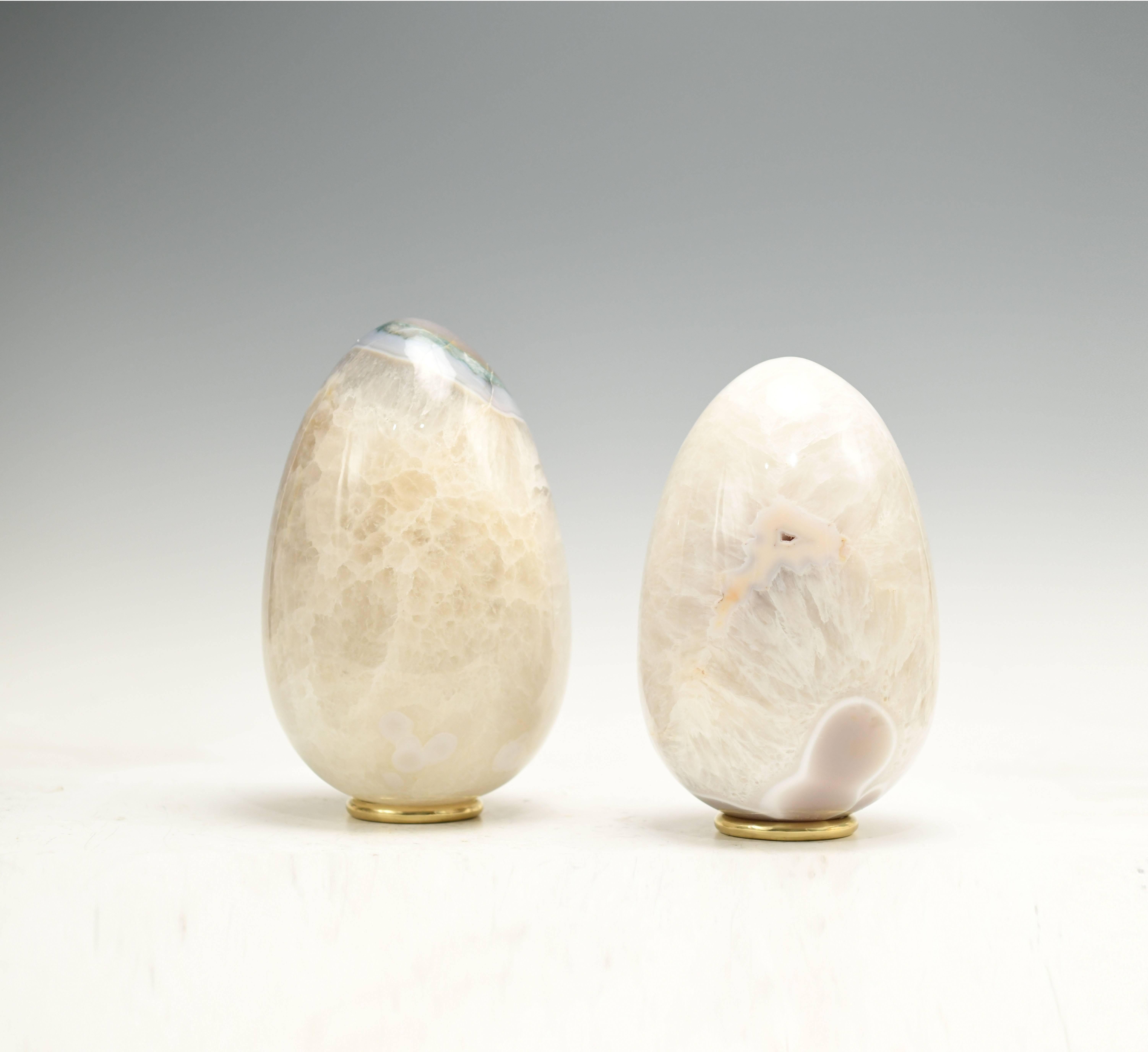 A group of two carved egg form agate sculptures with polish brass bases. 
The specimen was carved from larger natural agate into an egg form. Created by Phoenix Gallery.

Measures: The left one sculpture size is 6.25