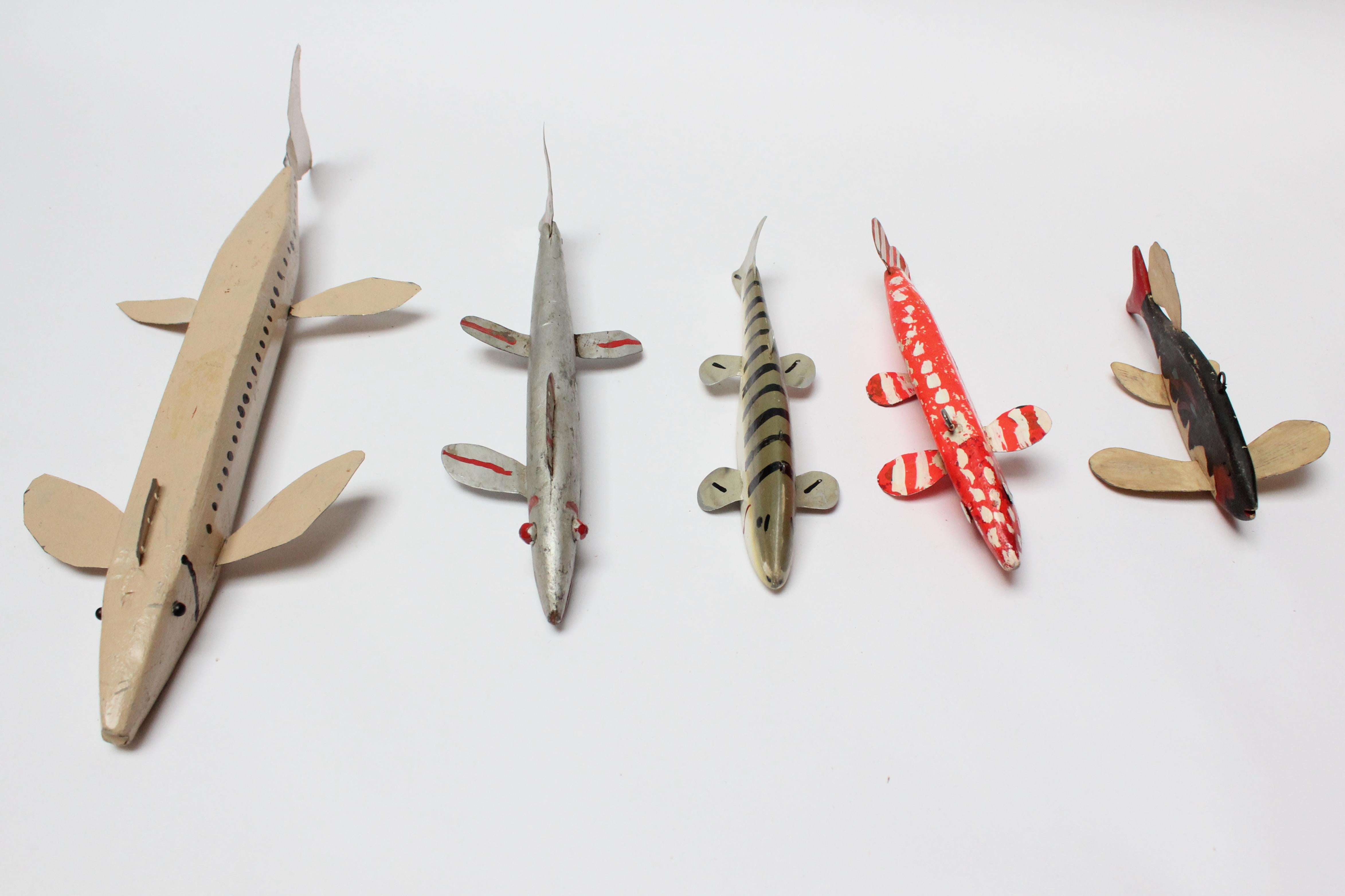 Group of five Folk Art fish decoys composed of painted tinned iron sheet metal or aluminum fins and tails and carved wooden weighted lead bodies, some with applied eyes; others with painted (ca. 1940s-1950, USA). The only non-weighted / all carved