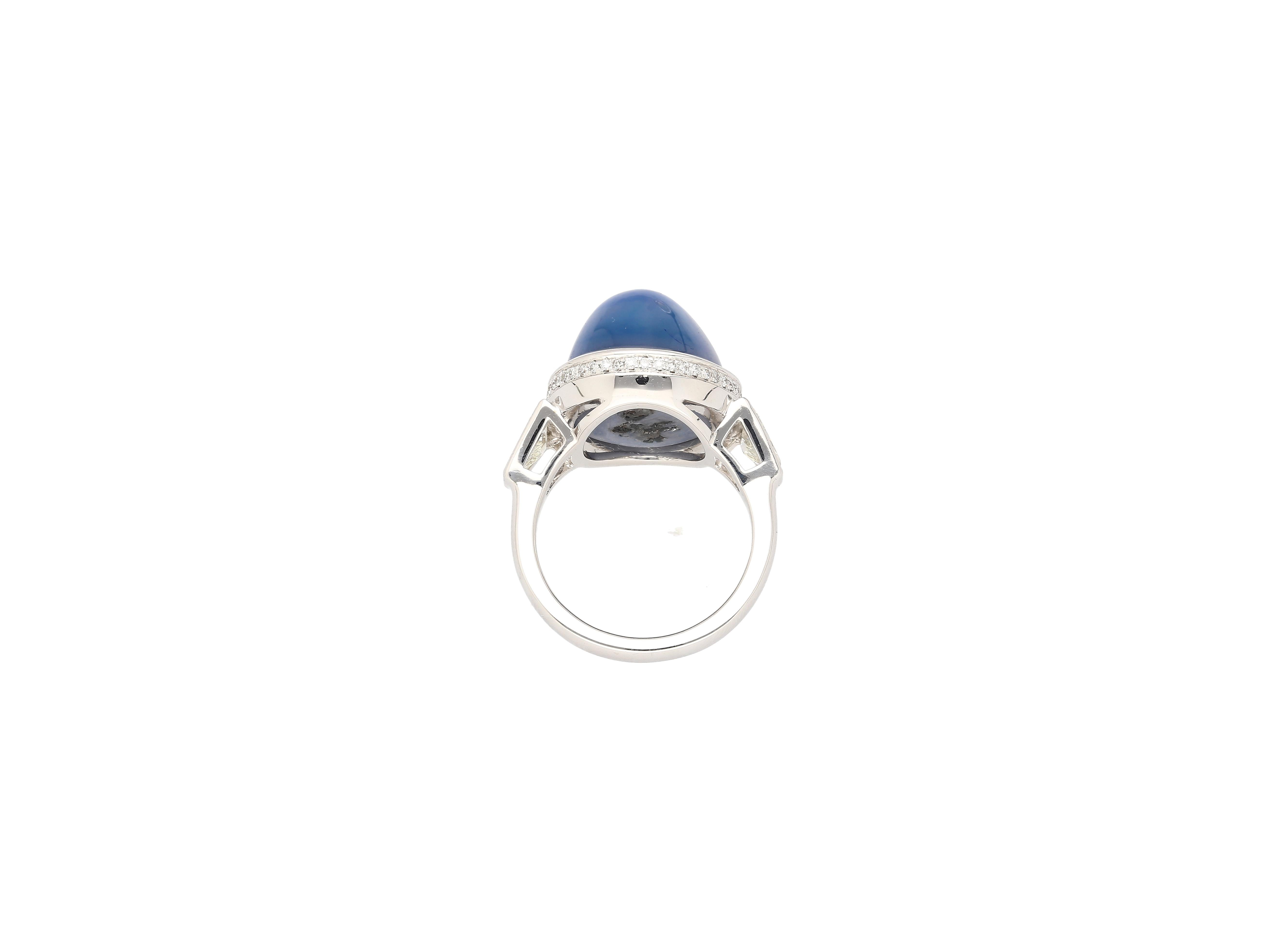 GRS certified 23.28 carat cabochon cut Blue Star Sapphire and diamond ring in 18k white gold. Set with 2 trapezoid cut diamond side stones, and a round cut diamond hidden halo. Offering the aesthetic of a vintage bezel setting, while displaying a