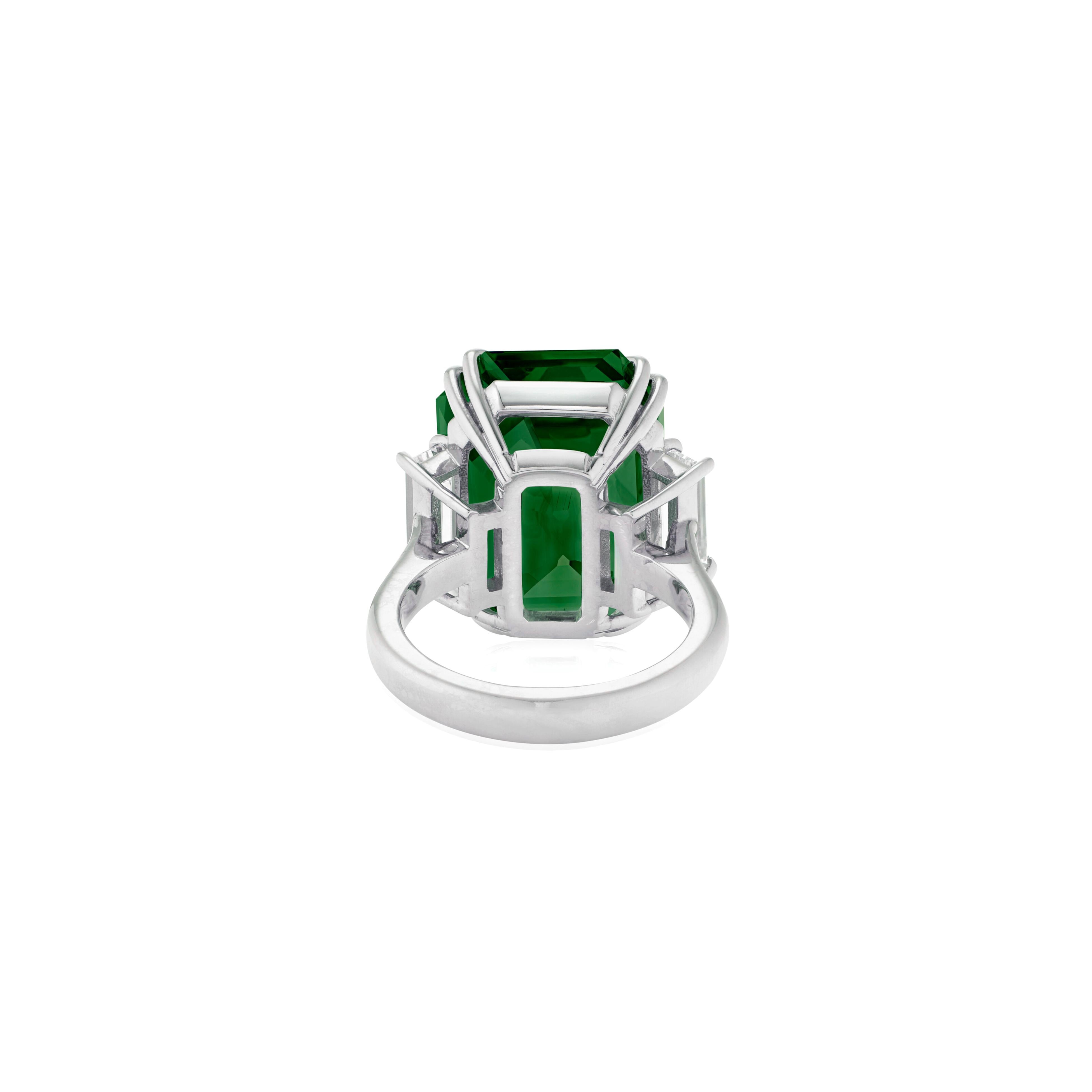 Dieser atemberaubende Ring besteht aus einem zertifizierten natürlichen Smaragd mit einem Gewicht von 12,60 Karat, der durch elegante Diamanten im Trapezschliff auf beiden Seiten ergänzt wird. Das leuchtende Grün des Smaragds wird durch die