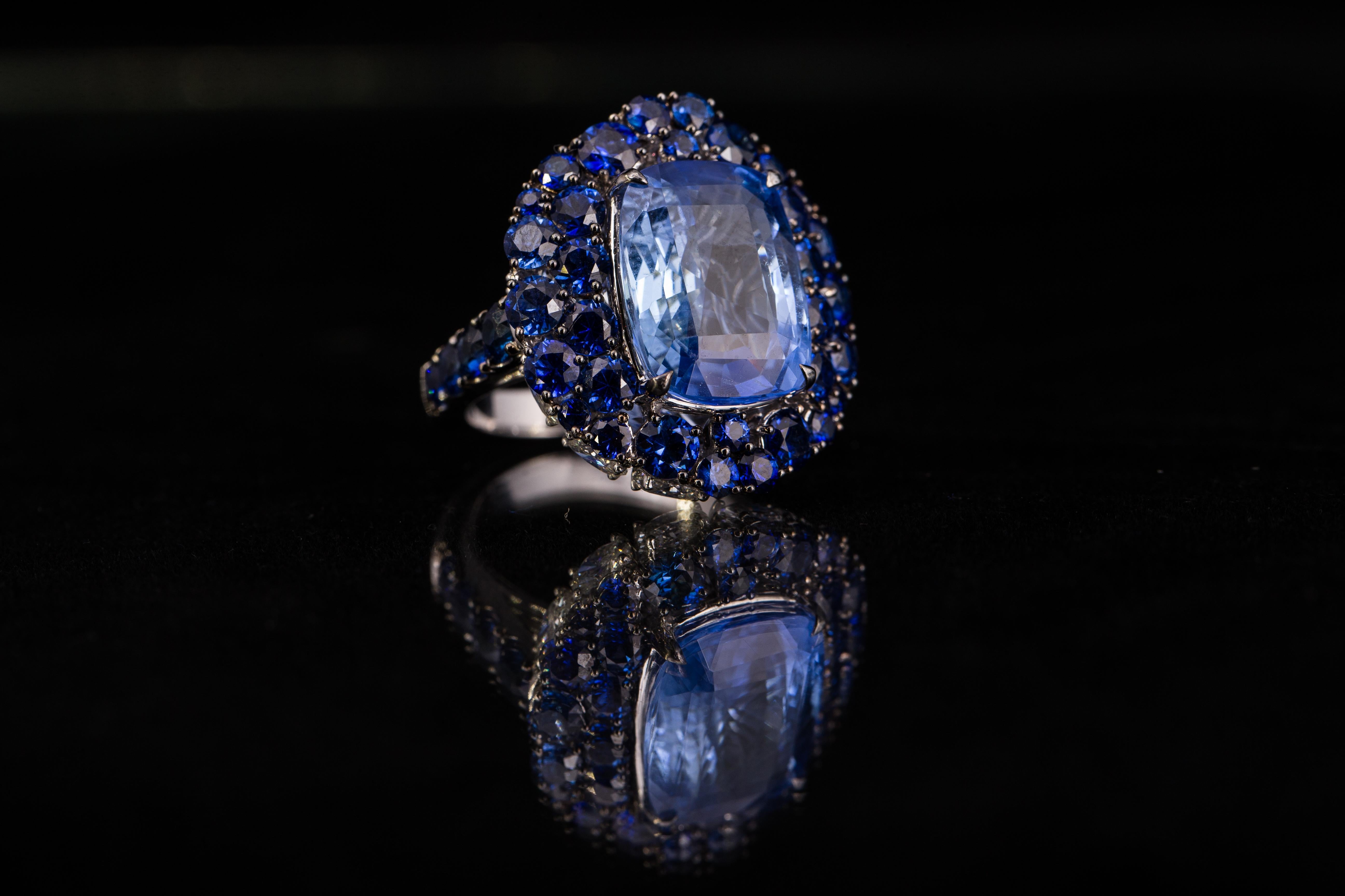 The beautiful, cushion cut, center stone is a 13.42 carat unheated Burmese sapphire (GRS certified) and is surrounded by 6.31 Carats of deep blue round sapphires. 2.41 Carats of oval Diamonds line the outer perimeter of the ring. 
This ring is US