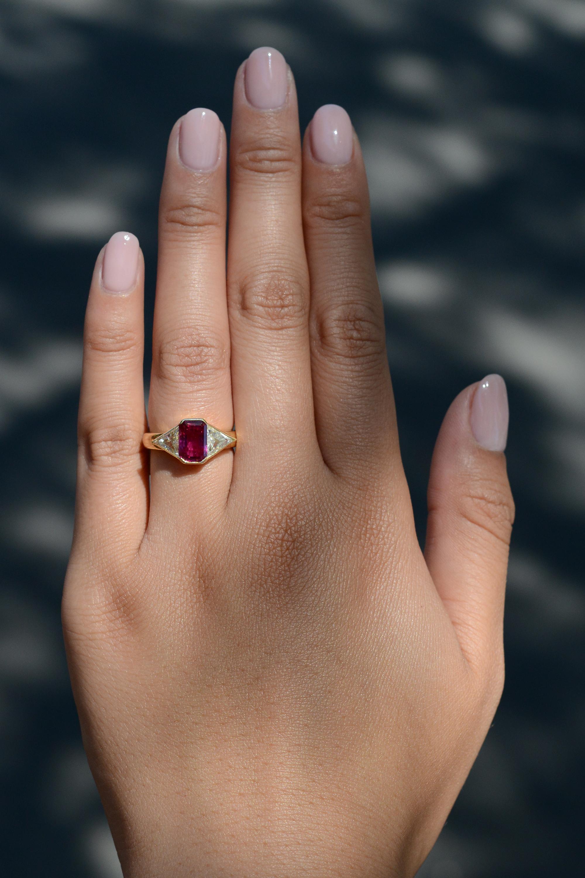 This classic 1980s vintage gemstone engagement ring is centered by a fantastic octagonal ruby, certified by the prestigious Swiss GRS laboratory and weighing over 2 carats. A classic 3 stone composition with a buttery, 18 karat yellow gold mount