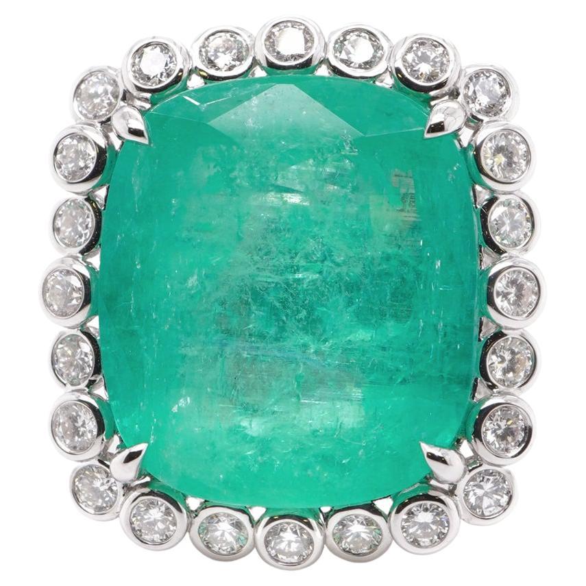 A gigantic 26 carat Colombian emerald which is GRS certified is set along with 2.09 carats of white brilliant round diamond. The GRS certificate can be found along side the images of the ring. 
Emeralds from Colombia possess less iron and fewer