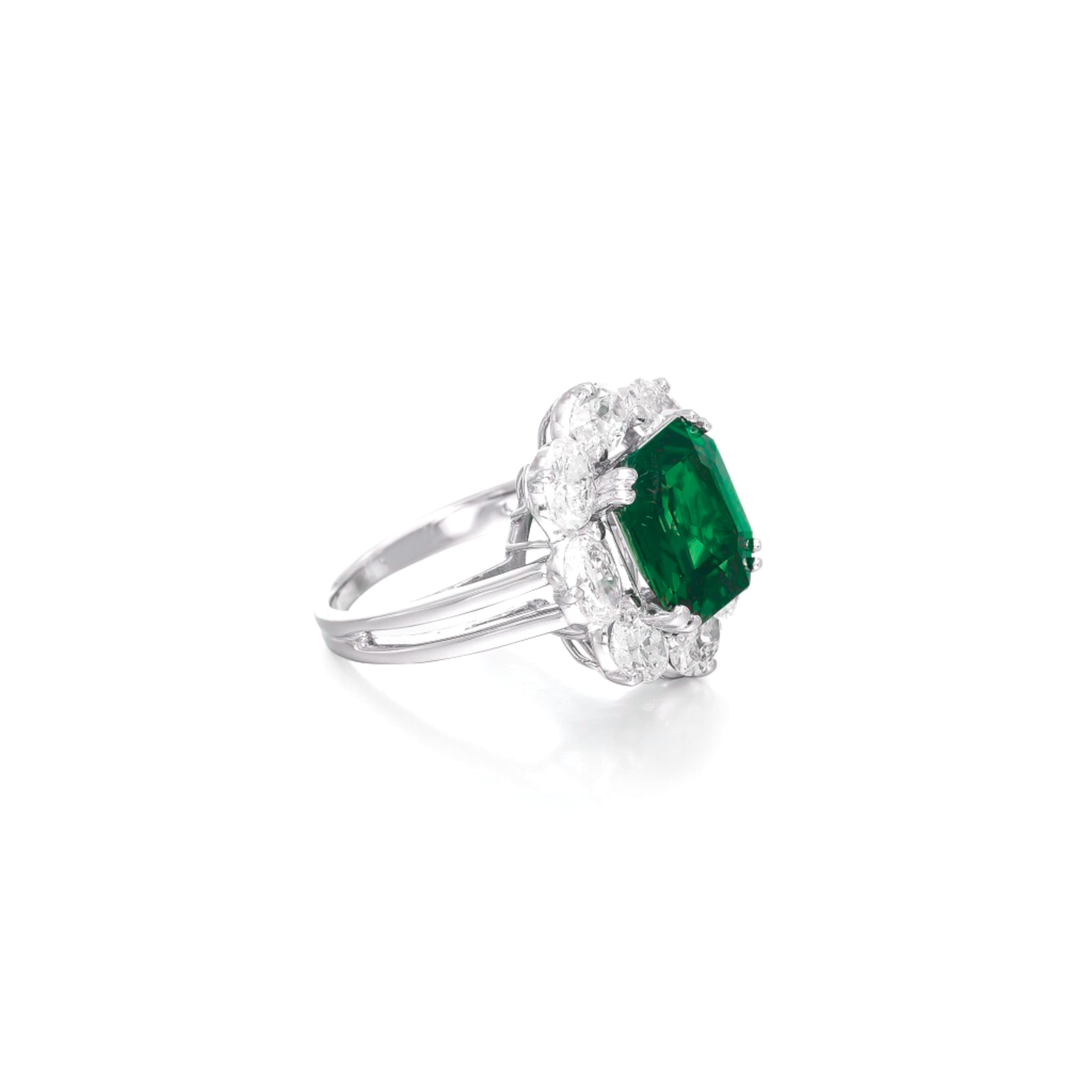GRS-carat emerald cut green emerald set in luxurious platinum, exuding elegance and sophistication. 

Flanking the center stone are pave round brilliant cut  diamonds, also graded D/E color, which enhances the overall aesthetic by providing a