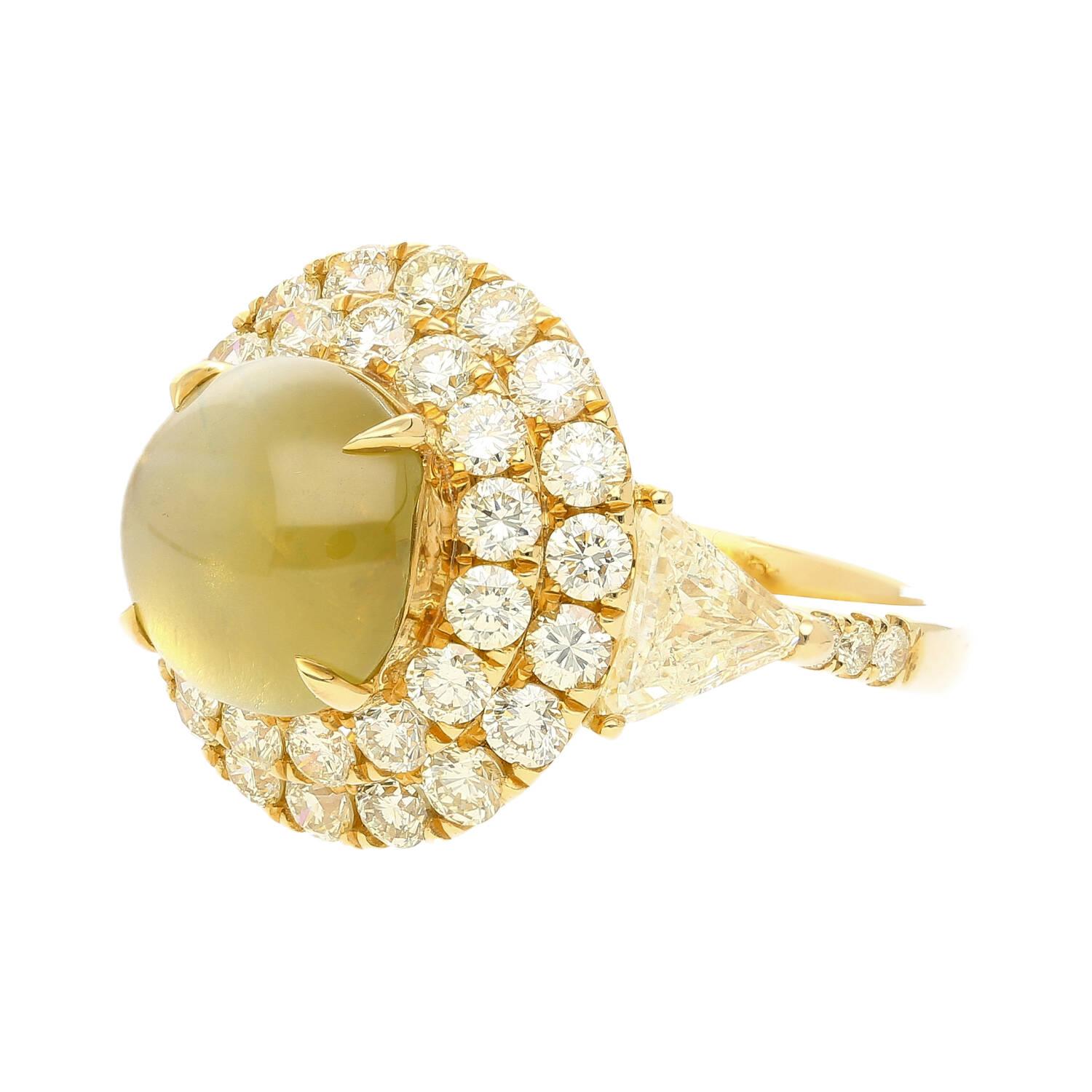 GRS Certified 5.12 Carat Chrysoberyl Cat's Eye and Double Diamond Halo Statement Ring With Trillion Cut Side Stones in 18K Yellow Gold. 

The center stone is natural, untreated, and features a perfectly centered chatoyancy (eye). Adorned by two