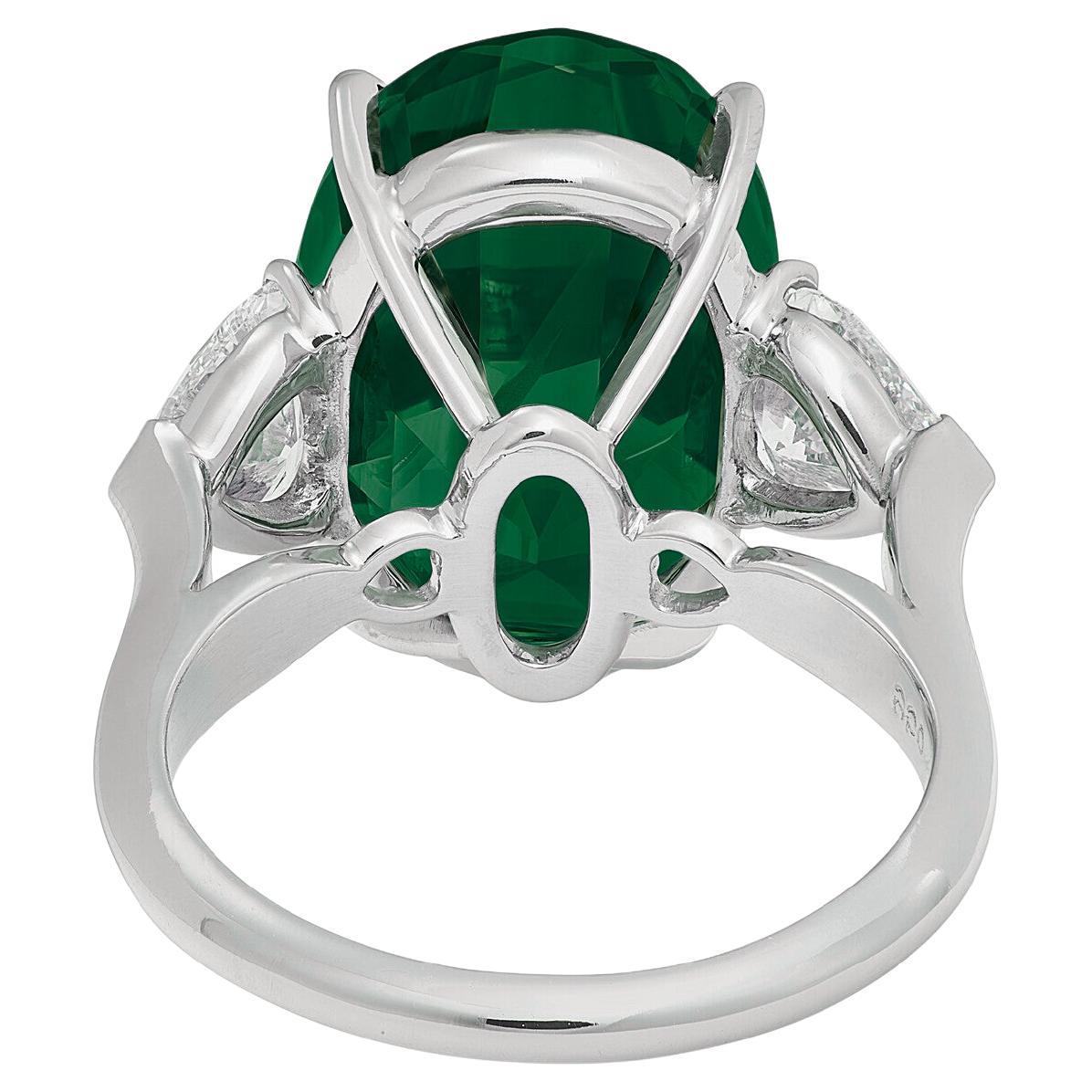 Experience the allure of luxury with this stunning 5.53-carat vivid green emerald, certified by GRS and expertly set in solid platinum. The vibrant emerald is complemented by two elegantly trilliant diamonds, adding a touch of sophistication and
