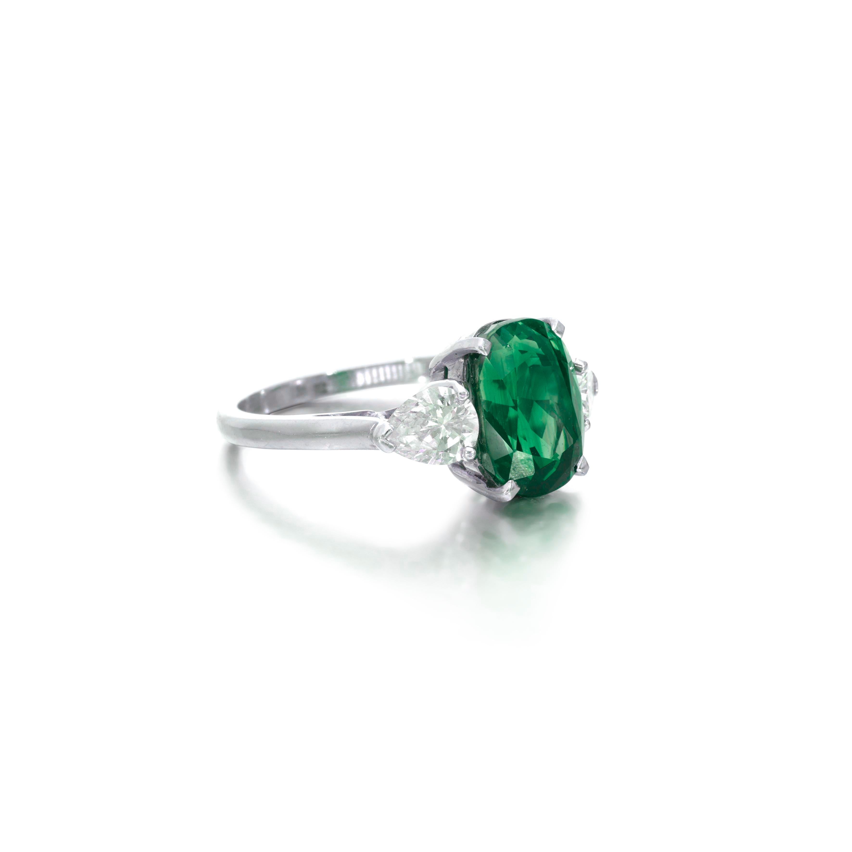 This exquisite emerald and diamond  ring features a bright green oval-shaped emerald at the center, surrounded by a glittering halo of diamonds and emeralds. 
Crafted in platinum 

The center stone is a 5.57ct oval emerald with very well saturated