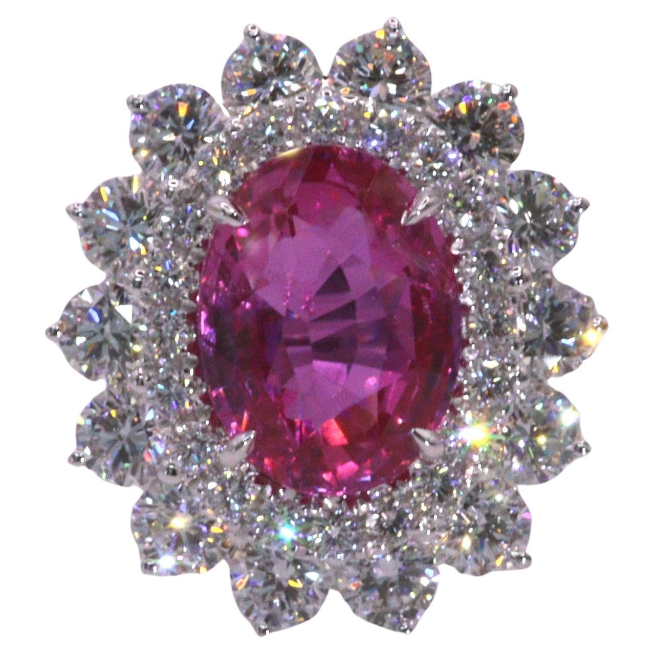 Prepare to be captivated by the enchanting beauty of this exquisite GRS Certified 5.41 Carat Sapphire, boasting a rare Vivid Pink color in an elegant oval shape. This remarkable gemstone takes center stage in a cluster-style ring, encircled by
