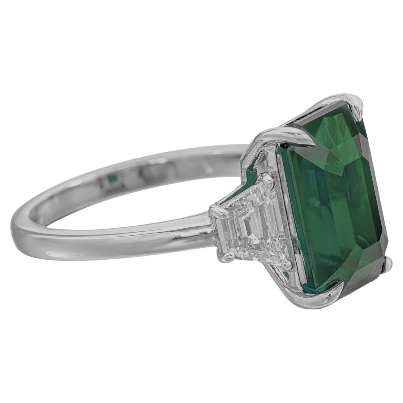 Centering an emerald-shaped emerald, flanked by two trapezoids shaped diamonds.

emerald weighing 6.15 carats
Size 6
Platinum
Accompanied by Grs report  stating that the emerald is of Zambian origin, with vivid green color

