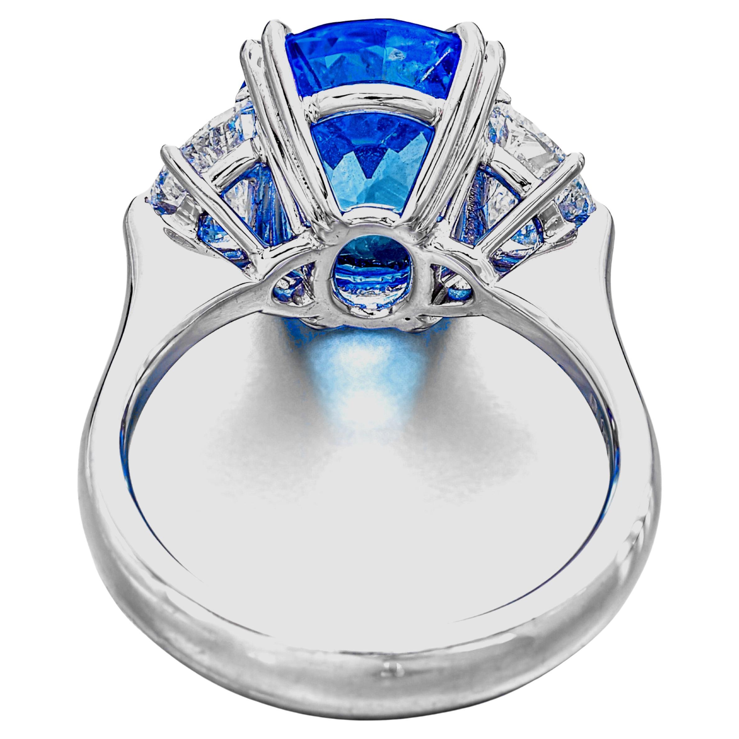 A magnificent statement of refined luxury, this exceptional three-stone ring features a 6.57 carat vivid blue sapphire, certified by C.Dunaigre as natural and of Ceylon origin. Masterfully cut in a classic oval shape, the emerald displays rich