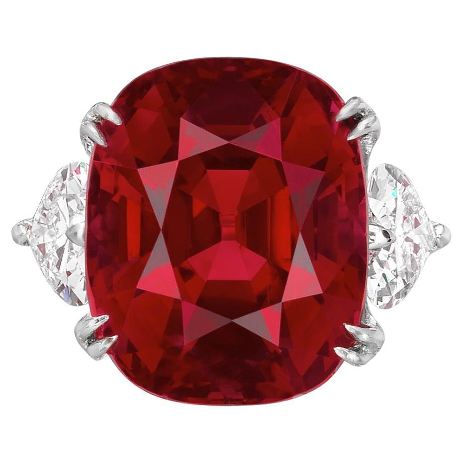 Questo squisito anello a tre pietre è caratterizzato da un rubino rosso vivo di Ceylon da 7,19 carati, certificato dal GRS. La gemma mostra un  saturazione e brillantezza eccezionali, senza alcun trattamento termico. Il taglio a cuscino enfatizza la