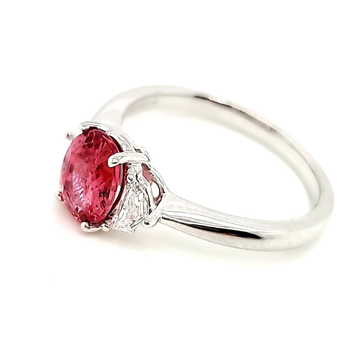 Imagine the soft, rosy glow of a summer sunset captured in the radiant hue of this 1.35-ct oval pink sapphire from Sri Lanka, accentuated by two dazzling trilliant-cut diamonds. 

Although the certificate has certified this as a pink sapphire, the