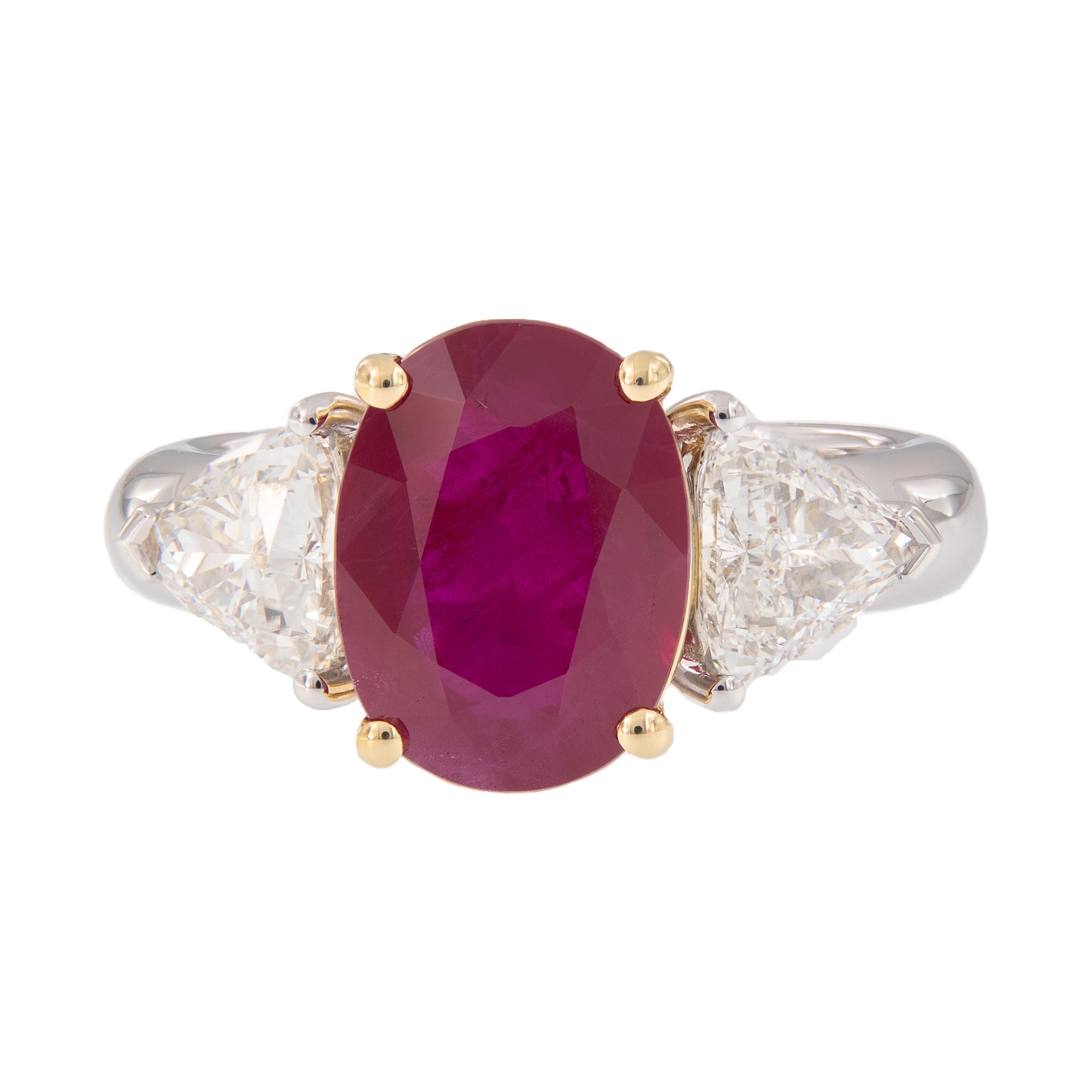 Make a statement with this beautiful and impressive 3-stone ring. The ring centers around a stunning 4.65 carat oval cut natural Burma ruby accented with two trillion-cut diamonds. The ruby is prong set and framed by 18k yellow gold and diamonds and