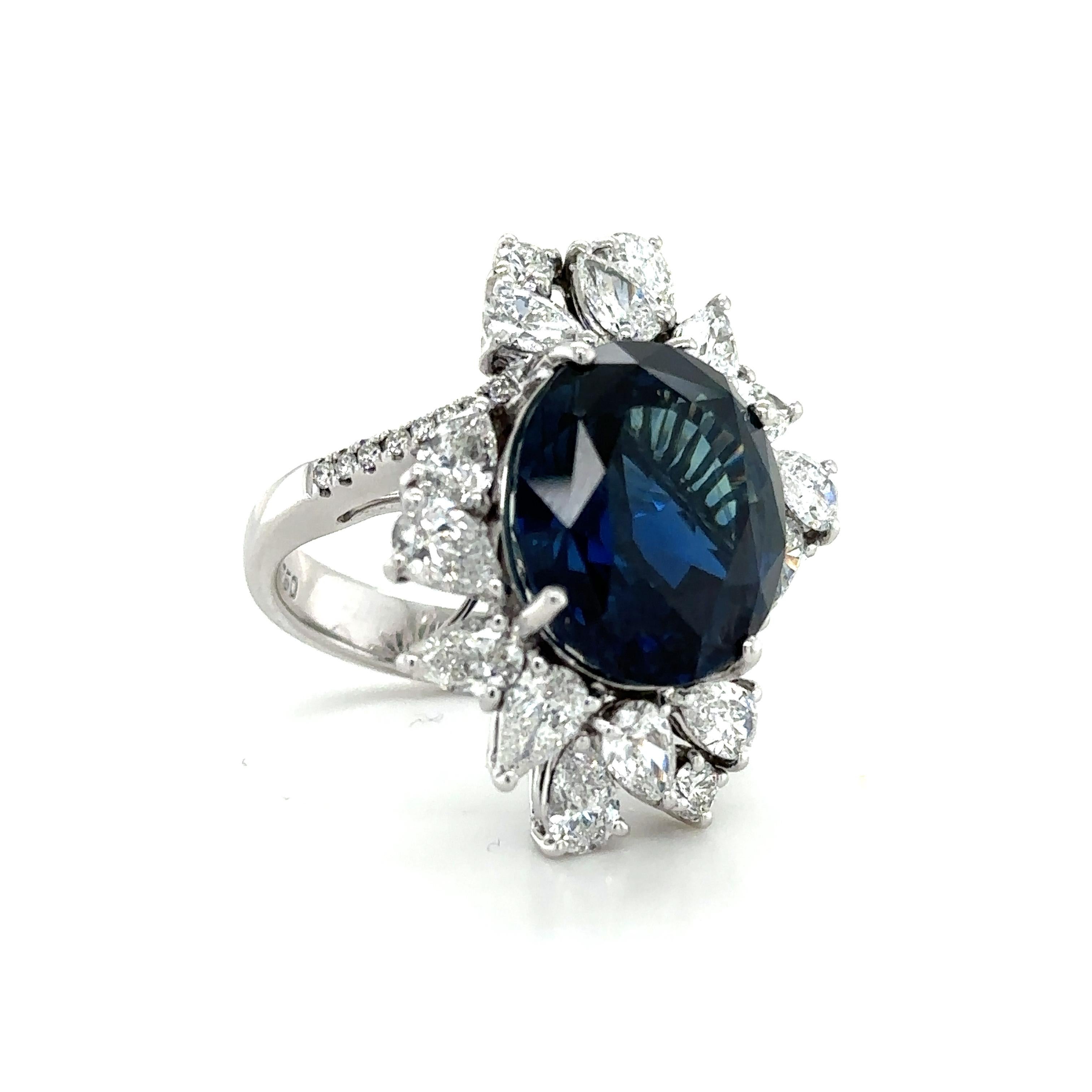 An exquisite ring set in 18k white gold, featuring a 15.57ct. Oval-cut Sapphire, surrounded by a total of 2.71ct of pear shaped diamonds, complimented with 0.27ct of round diamonds. 

The Sapphire is graded Deep Blue, a rich blue color, with strong