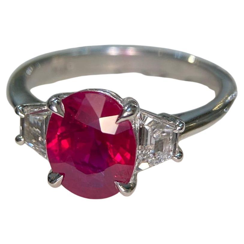 Introducing the exquisite GRS No Heat Certified 5 Carat Ruby Cushion Diamond Ring, adorned with trapezoid diamonds on the sides. At the heart of this remarkable ring lies a captivating oval-cut ruby, certified by GRS for its exceptional quality and