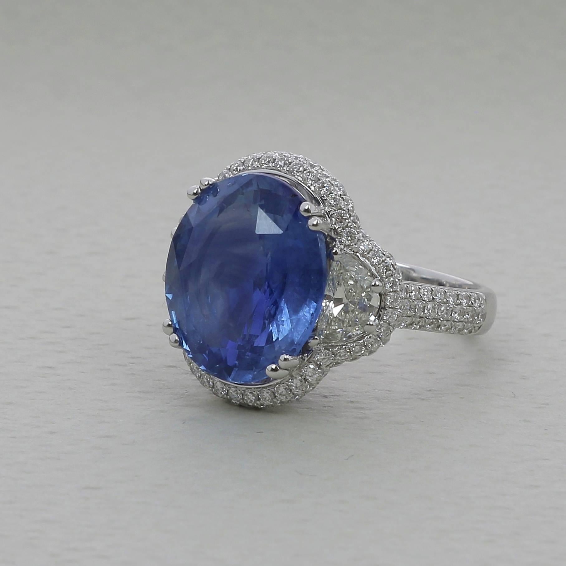 A Blue Sapphire Ring weighing 12.47 carats. The stone’s shape is oval, having for colors a striking Blue. 
The ring is set with two Half Moon Diamond weighing 0.91 Carats and 134 Round Diamonds weighing 0.89 Carats . 
The Diamond are GVS