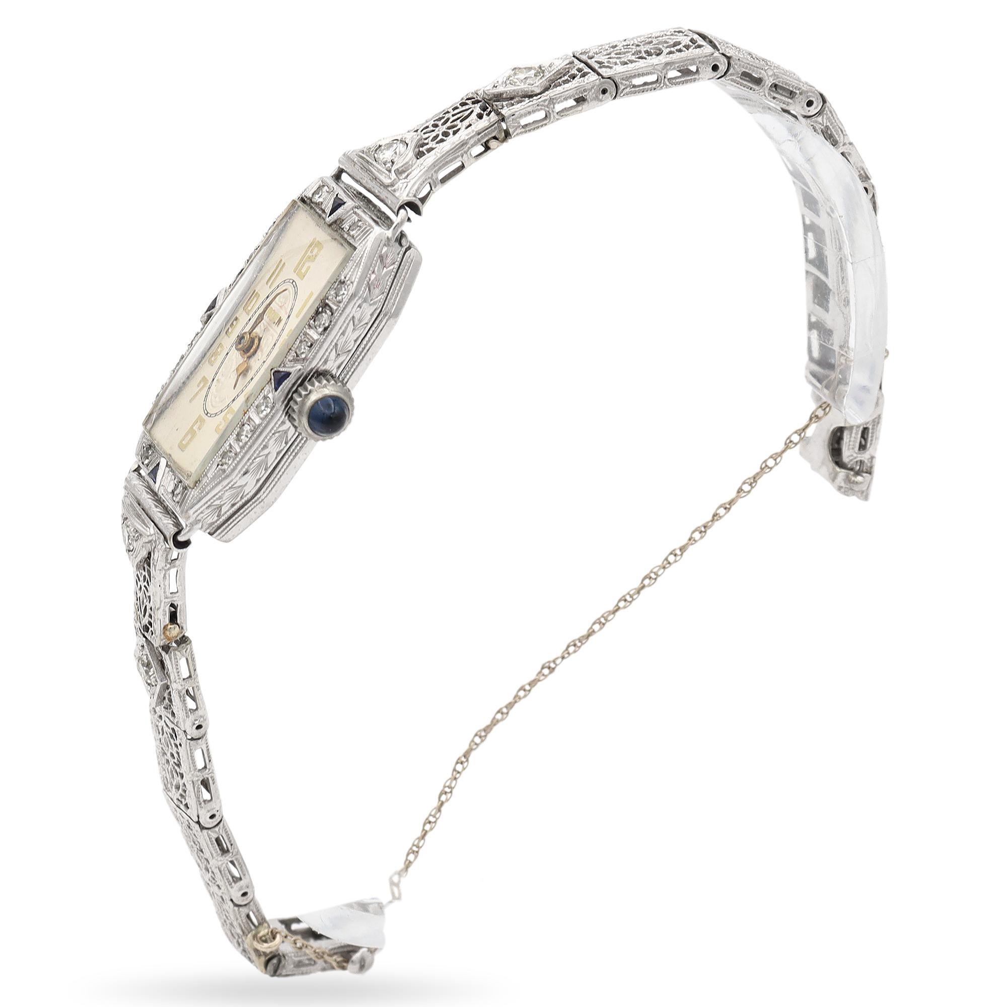 Elegant Vintage Gruen Platinum Diamond and Sapphire Watch. This exquisite timepiece is crafted with a blend of platinum and white gold, featuring intricate filigree detailing. The watch face is adorned with white diamonds, complemented by deep blue
