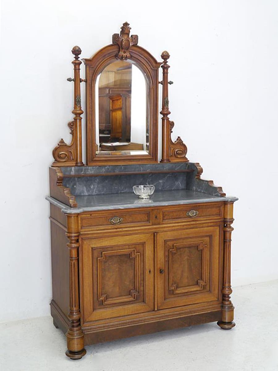 This antique amazing dresser / sideboard, Wilhelminian style circa 1880 is equipped with a mirror attachment.
The mirror chest of drawers is made of solid walnut and is partly veneered.
The facet cut mirror is held by two turned columns with cones