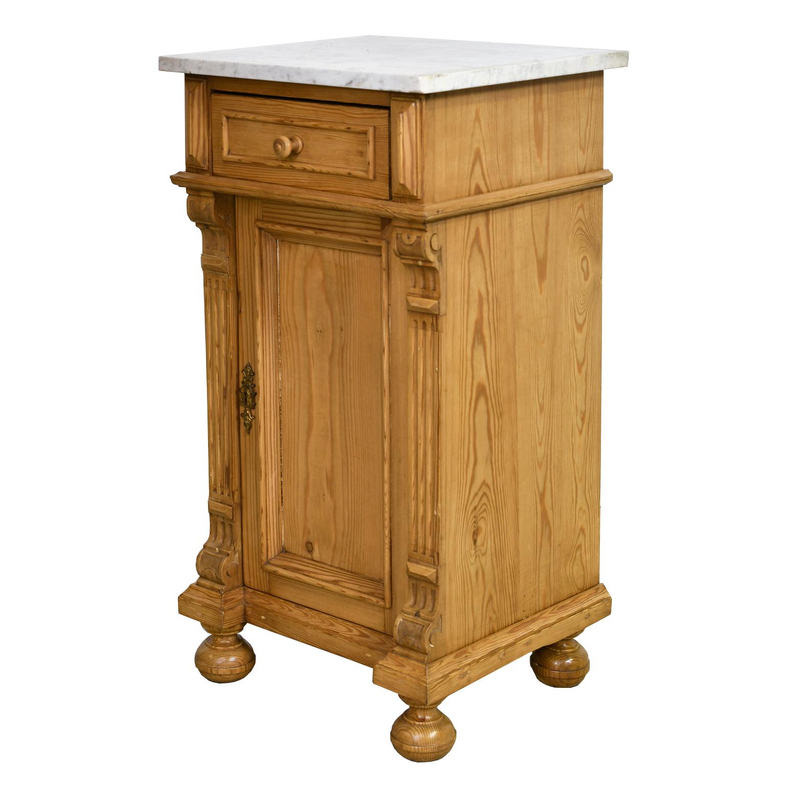 A lovely Gründerzeit pot cupboard or nightstand in pine with white Carrara-marble top, with one drawer over a lower cabinet that offers one interior shelf. Features decorative moldings around recessed panels on drawer and door, with fluting along