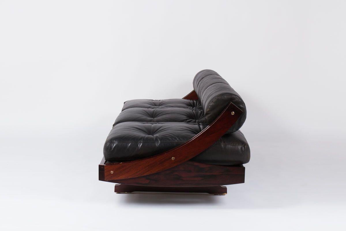 Functional and elegant lounge sofa/daybed model GS195 designed by Gianni Songia for Sormani, Italy 1963. This Italian sofa has a sculptural rosewood frame and very nice black leather cushions and seating. The hidden legs and high back rest creates