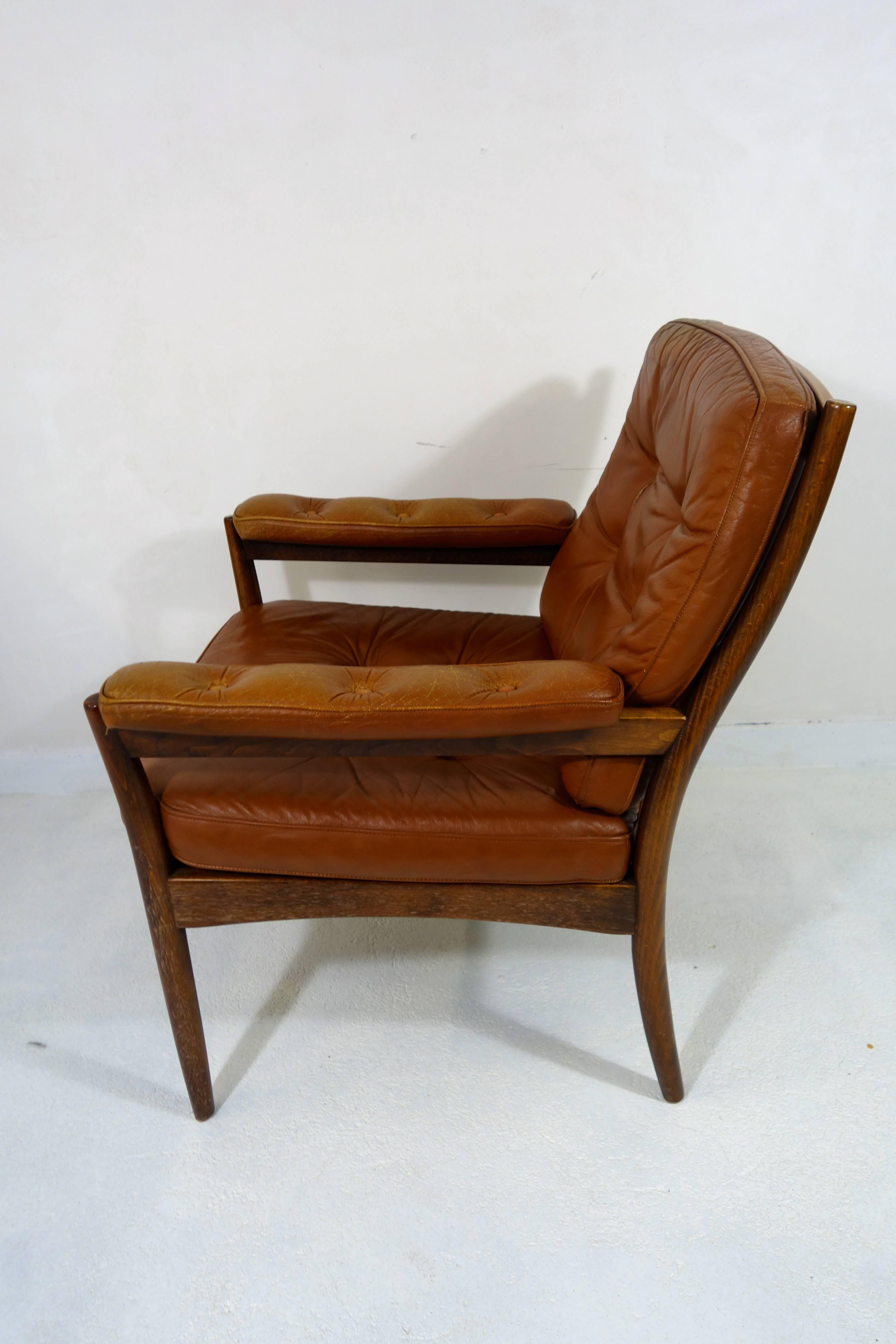 Pair of wooden armchairs designed in 1965 and produced by Göte Möbel Nassjö of Sweden. 
They have cushions made of cognac buttoned leather: seating cushion, back cushion and arm cushions, all with a wonderful patina.
Makers label marked on the frame.